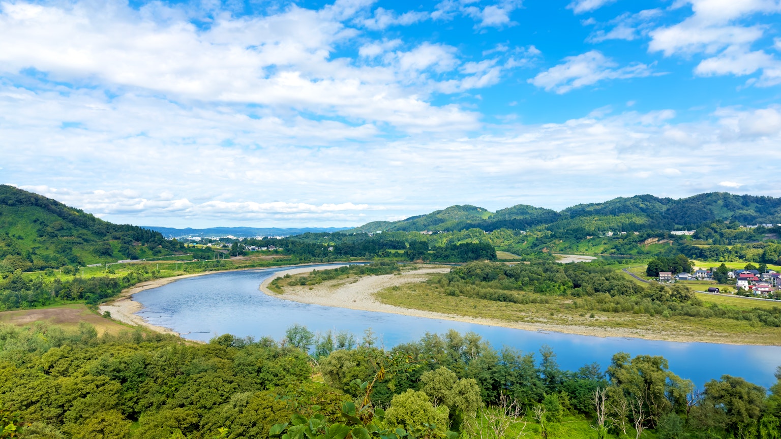 蜿蜒河流的美景，周围环绕着郁郁葱葱的绿色和蓝天