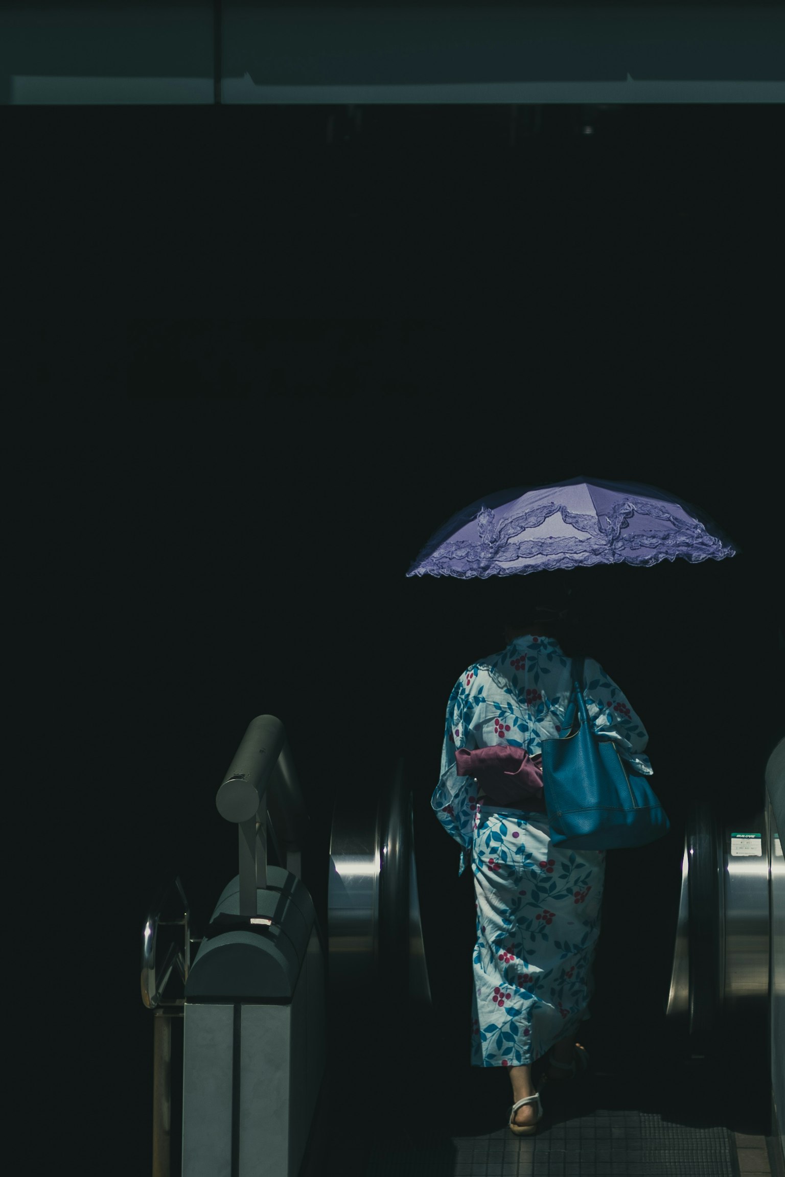 一位穿着和服的女性拿着紫色伞正在下扶梯