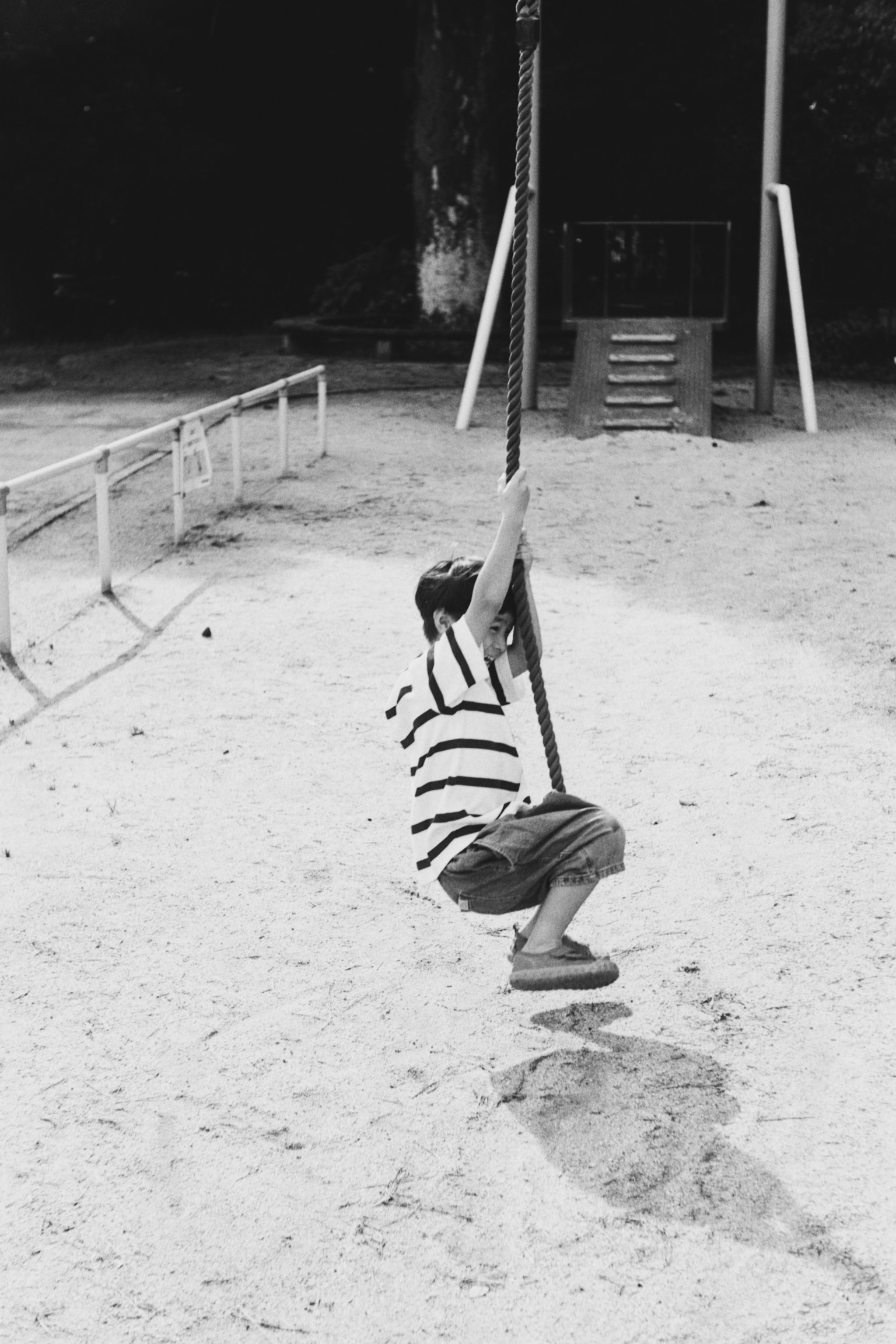公園のブランコで遊ぶ子供の白黒写真