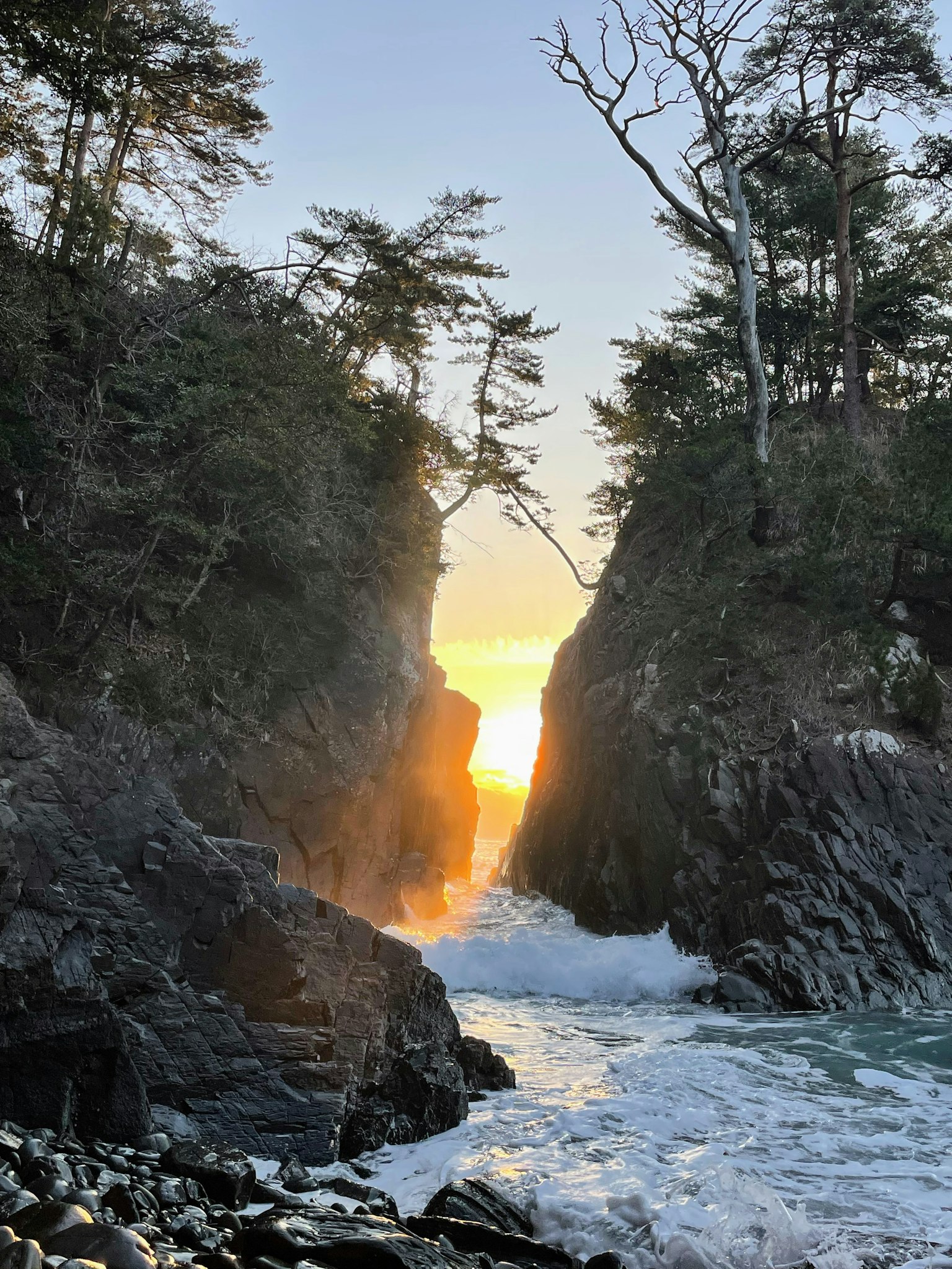 Vista escénica del atardecer entre acantilados rocosos y olas del océano