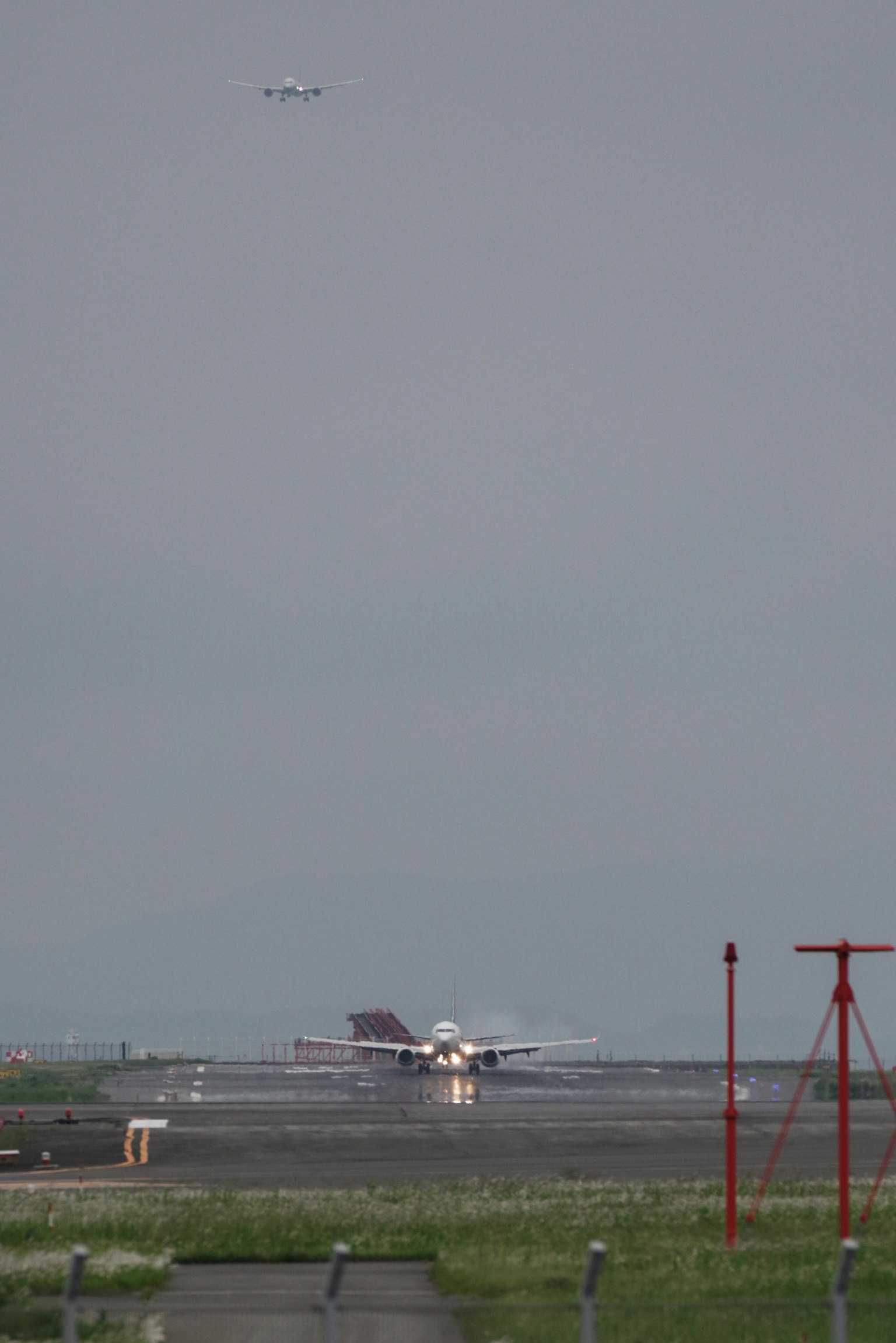 Blick auf einen bewölkten Himmel mit einem Flugzeug, das auf einer Landebahn landet, und einem anderen Flugzeug darüber