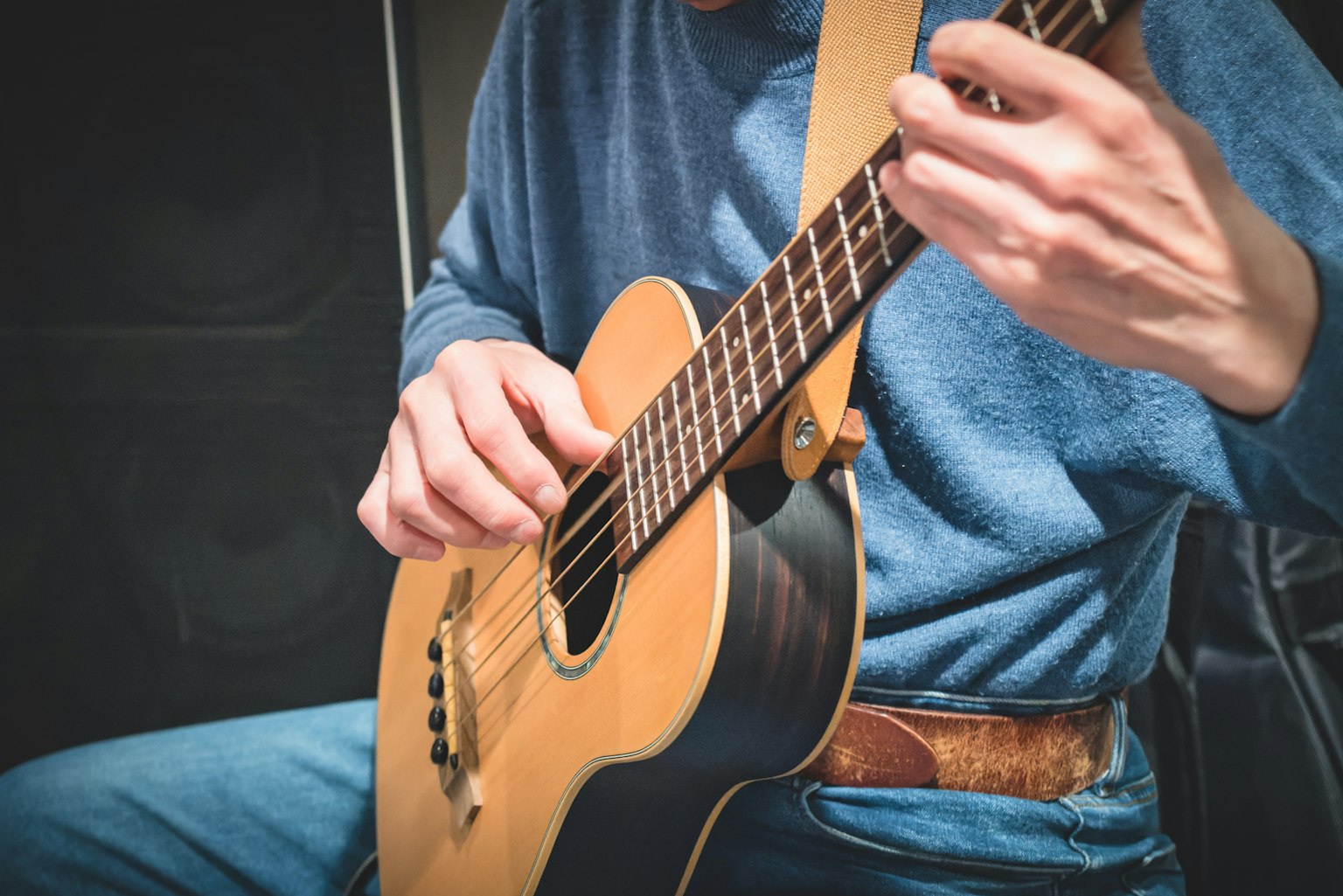 Close-up tangan seorang pria yang bermain gitar akustik