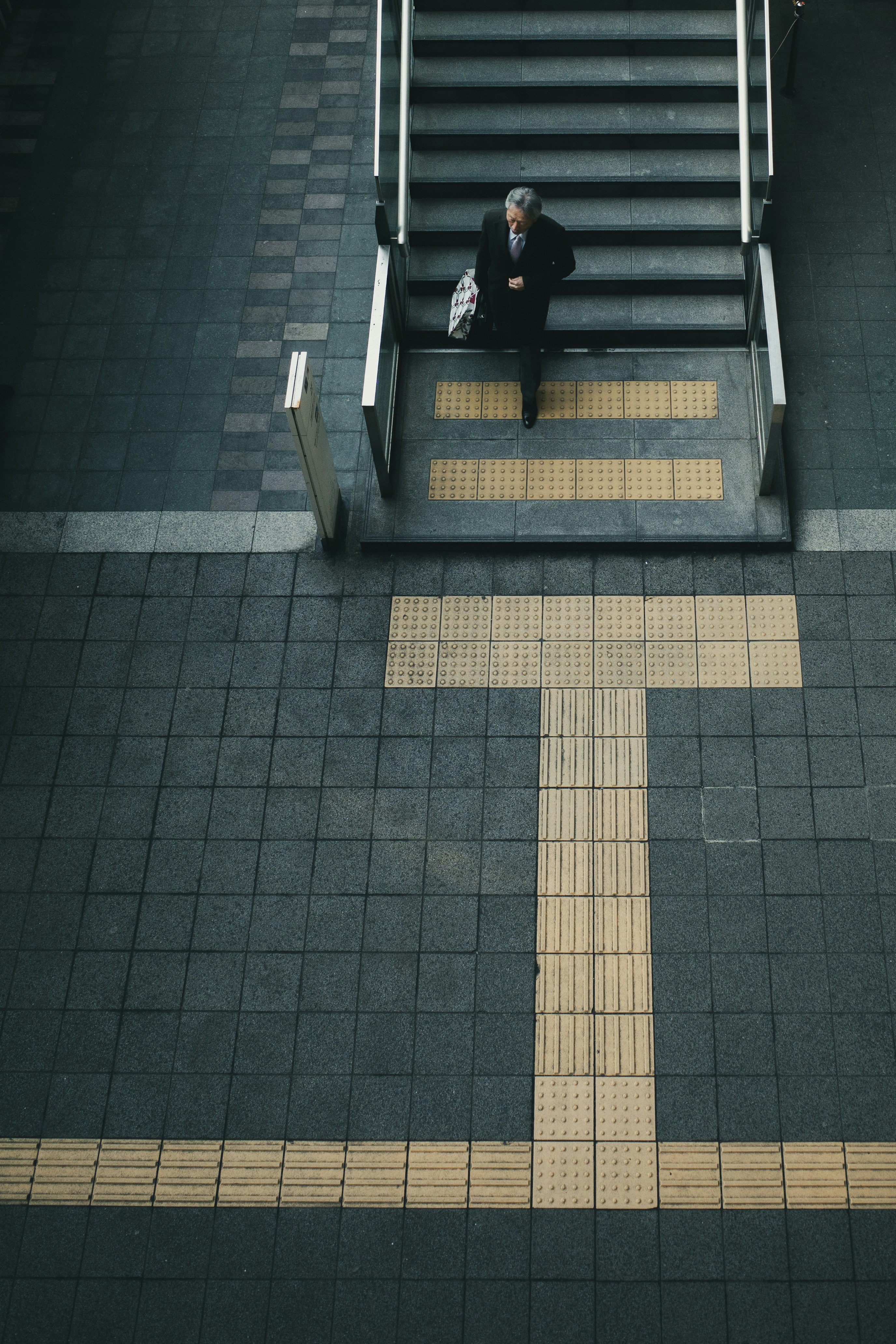 博多駅の階段と点字ブロックのある通路で立つ人物