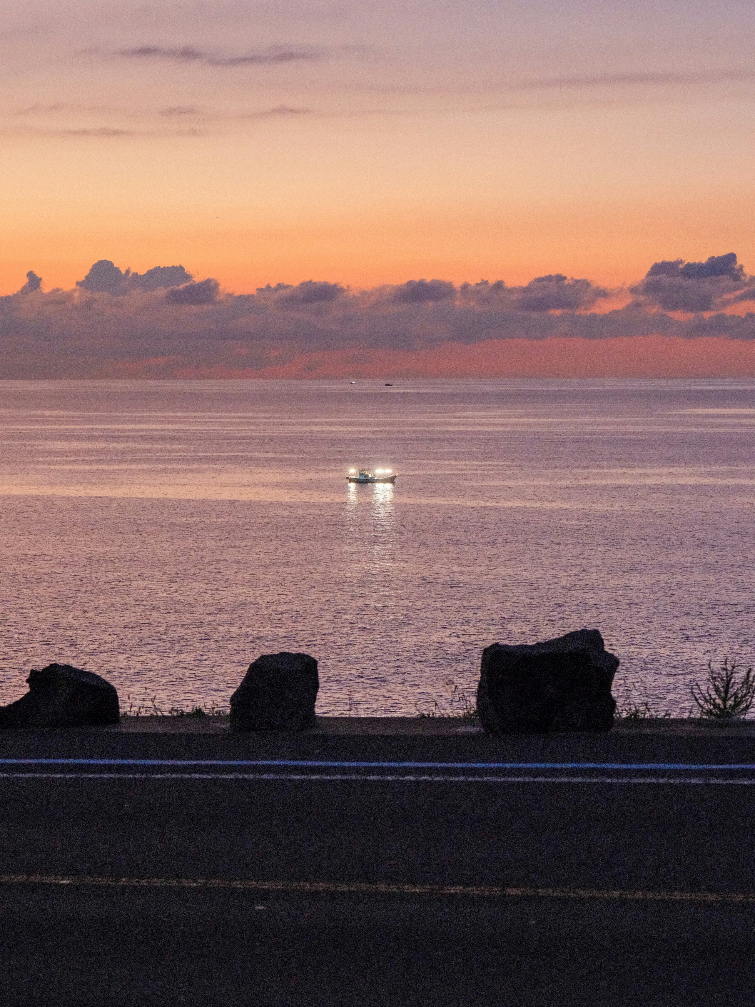 夕焼けの海と水平線に浮かぶ小舟