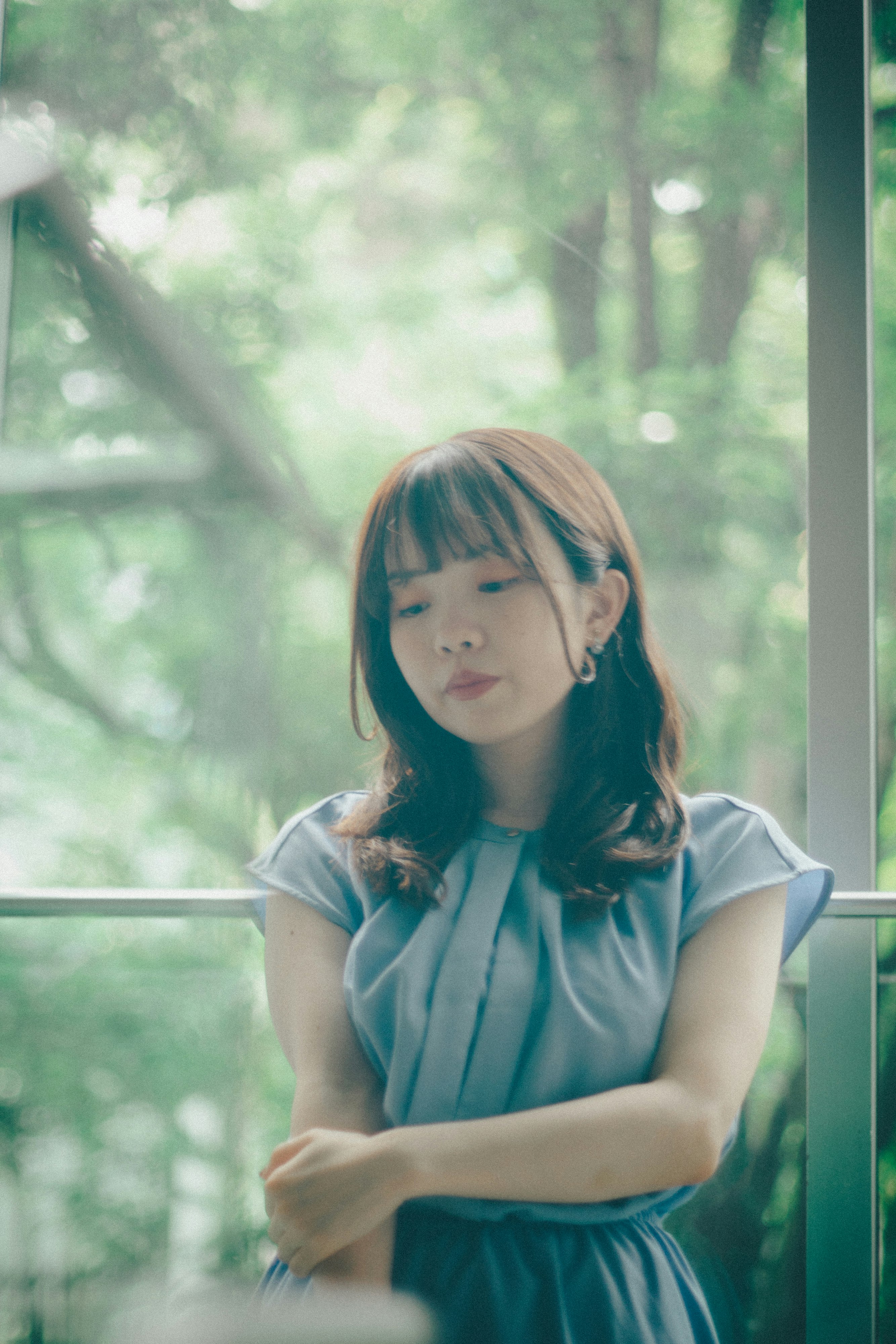 窓辺に立つ青いワンピースの少女