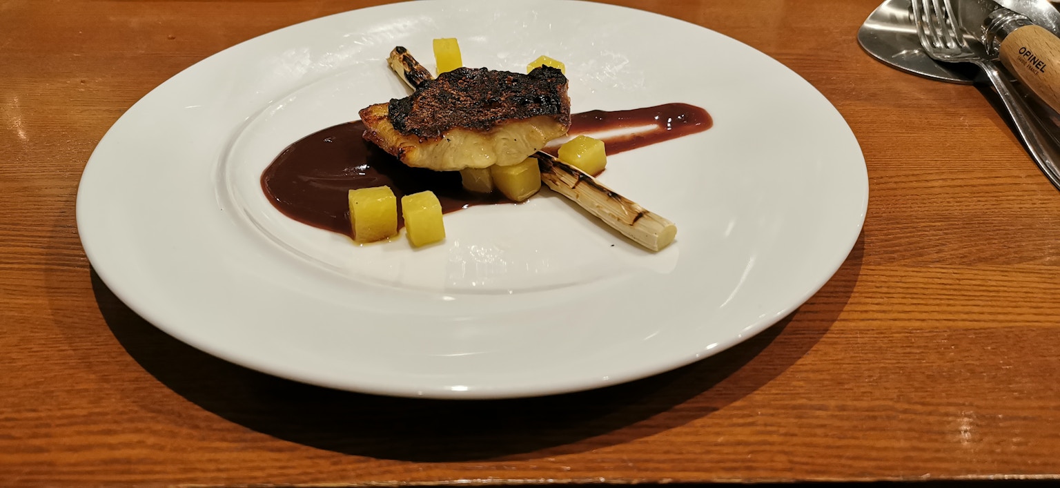 Piatto grigliato servito su un piatto bianco con salsa dolce e cubetti di frutta