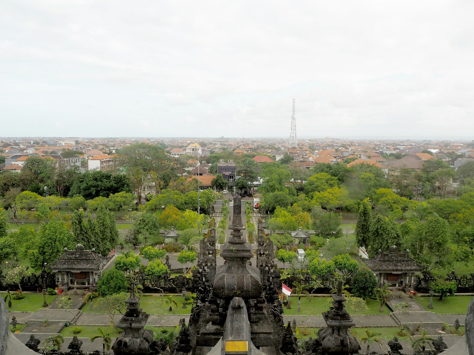 Pemandangan indah sebuah kuil Bali dengan taman rimbun dan pemandangan kota