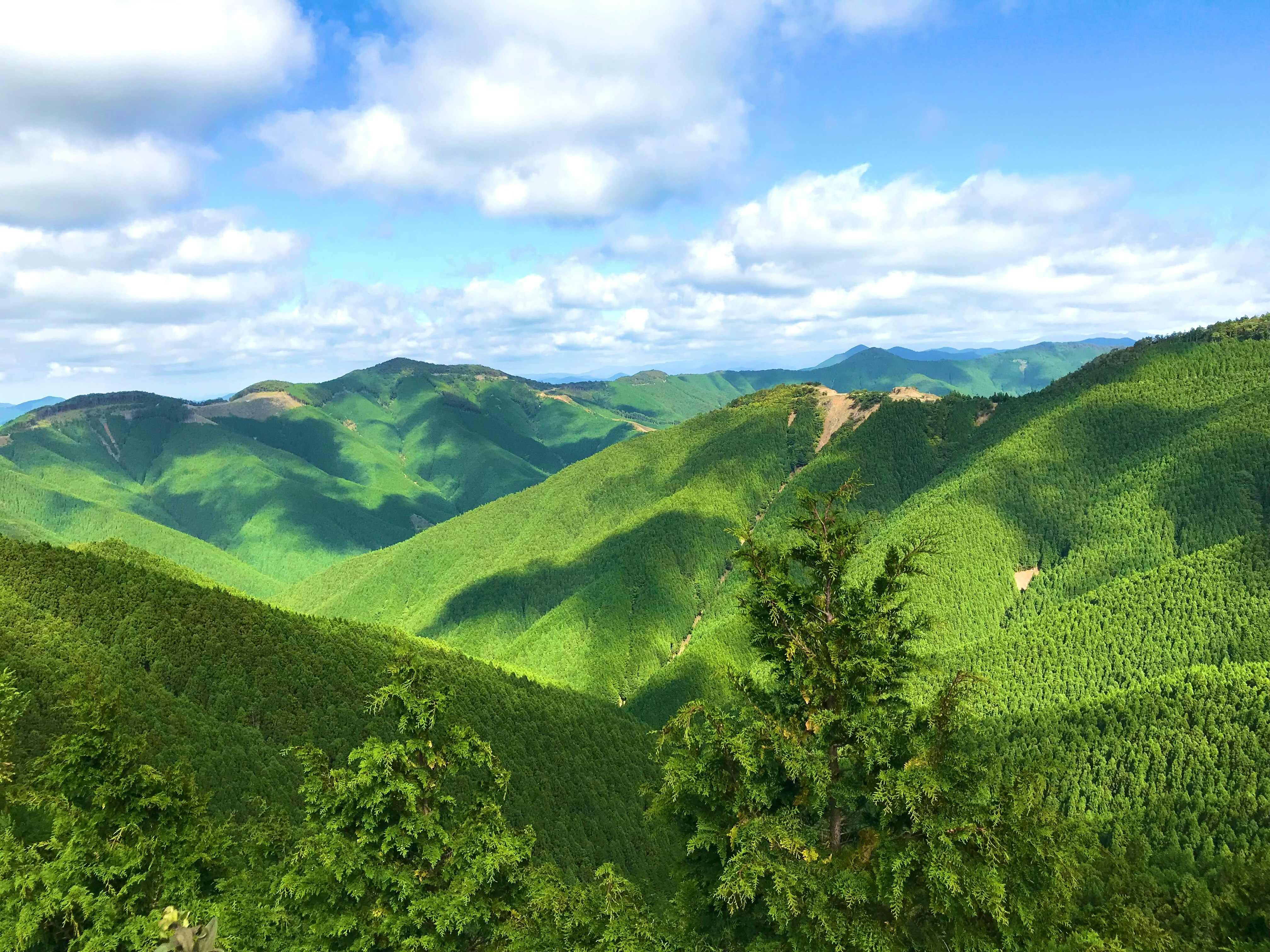 green mountain ranges under a wide cloudy sky