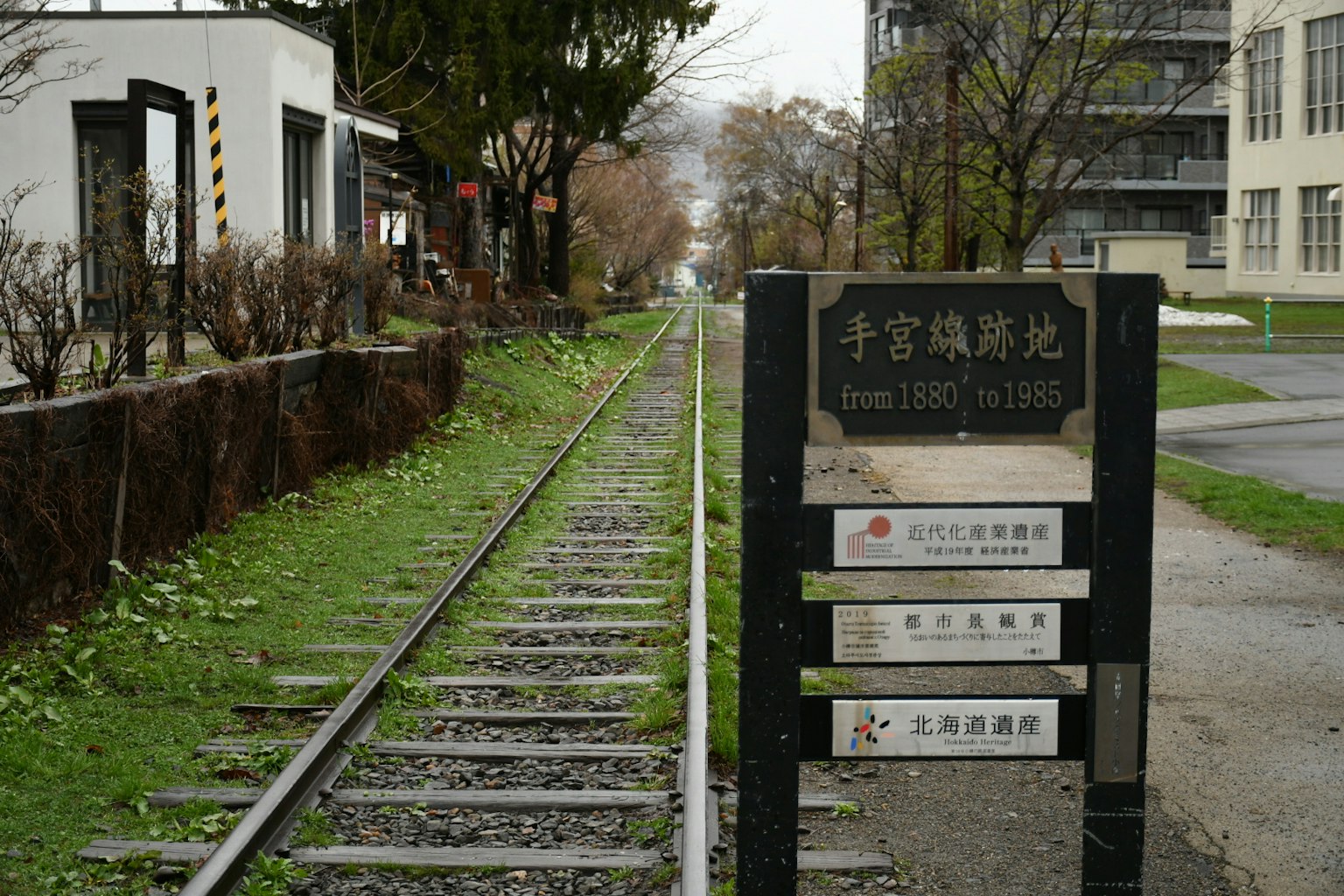 ทิวทัศน์ที่มีรางรถไฟและป้ายอยู่ท่ามกลางต้นไม้และพืชสีเขียว