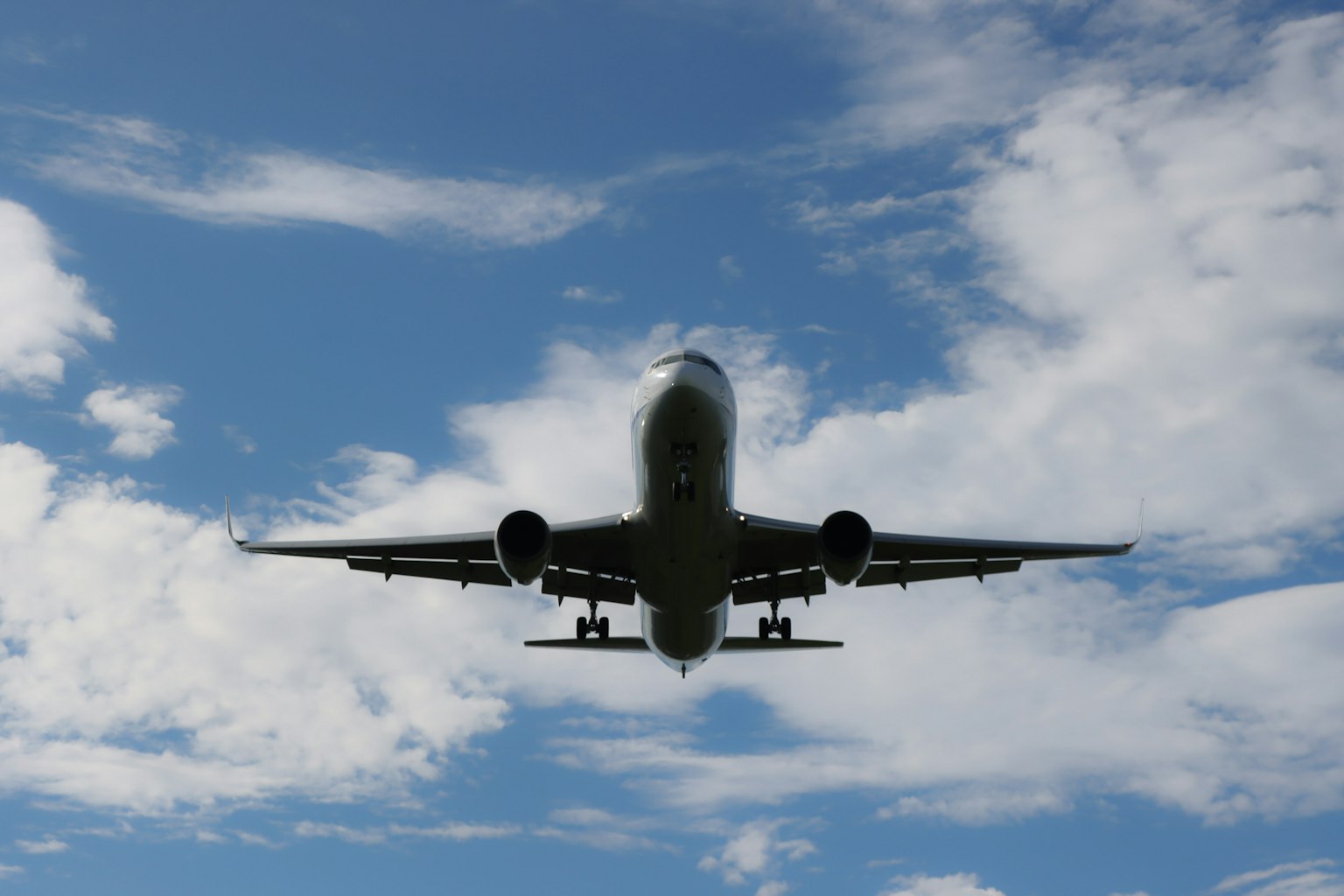 Airplane flying against a blue sky with clouds