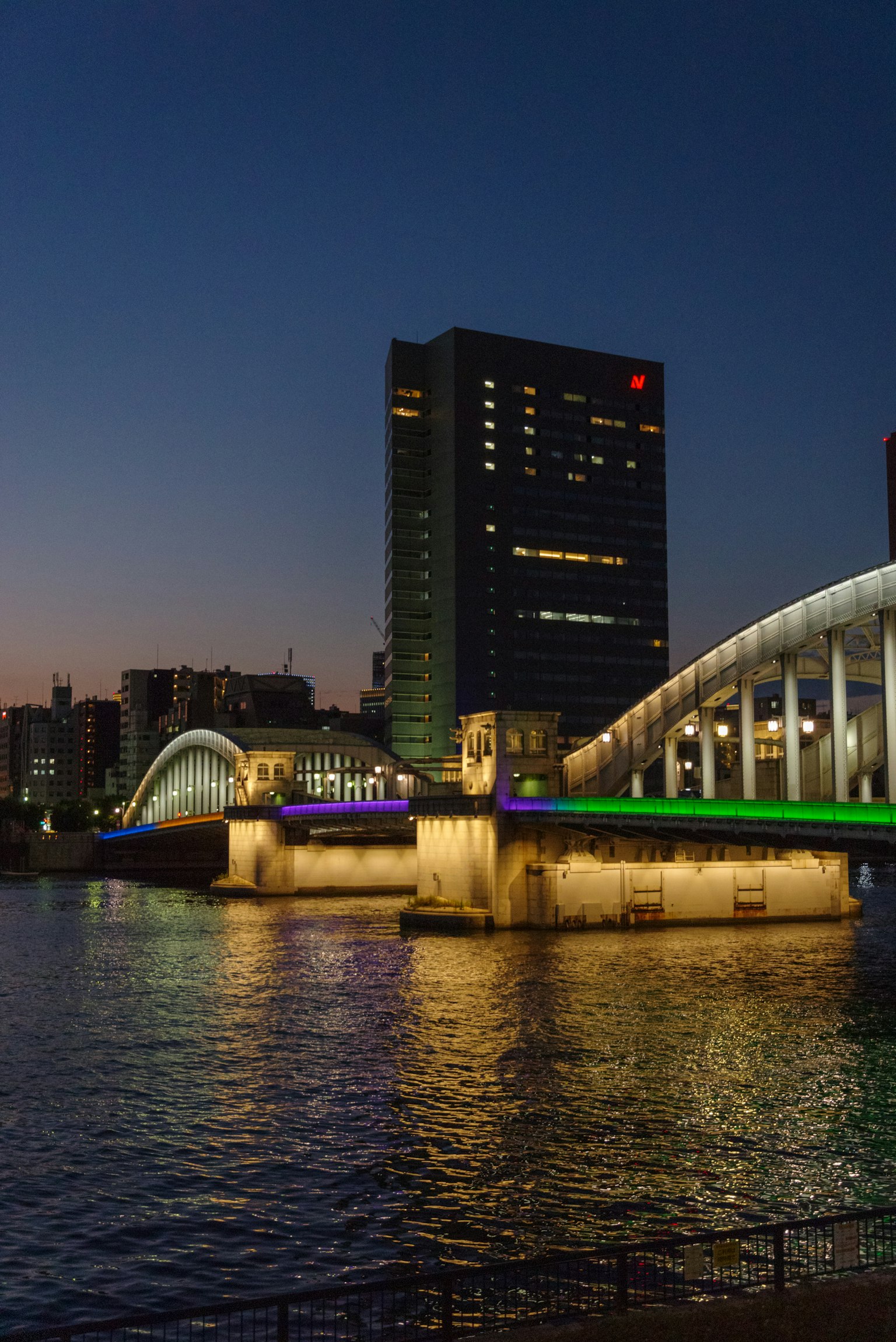 Ponte illuminato e edificio moderno lungo il fiume di notte