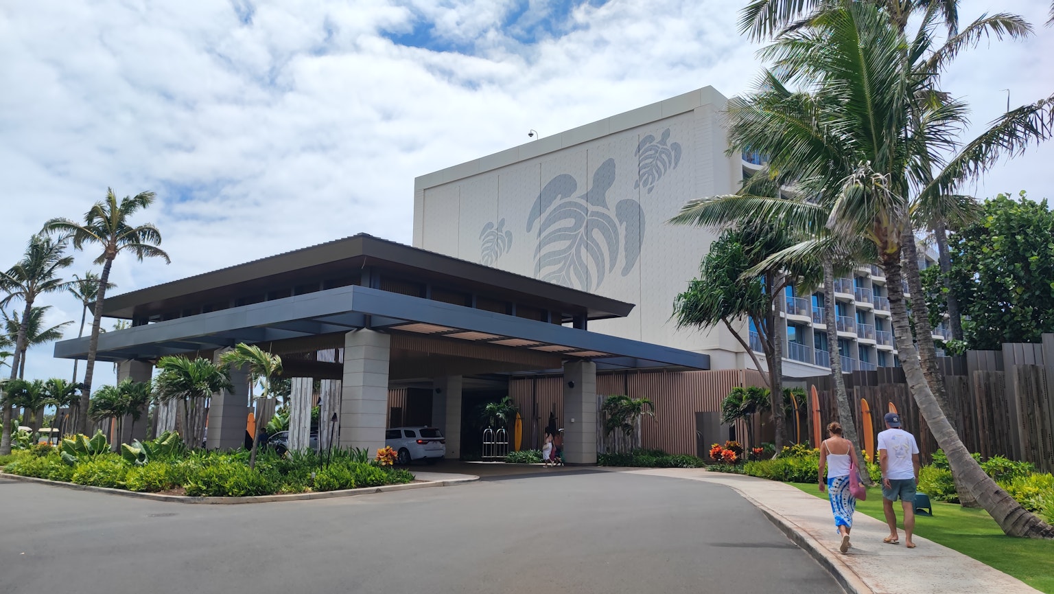 Pintu hotel resor dengan tanaman tropis dan langit mendung