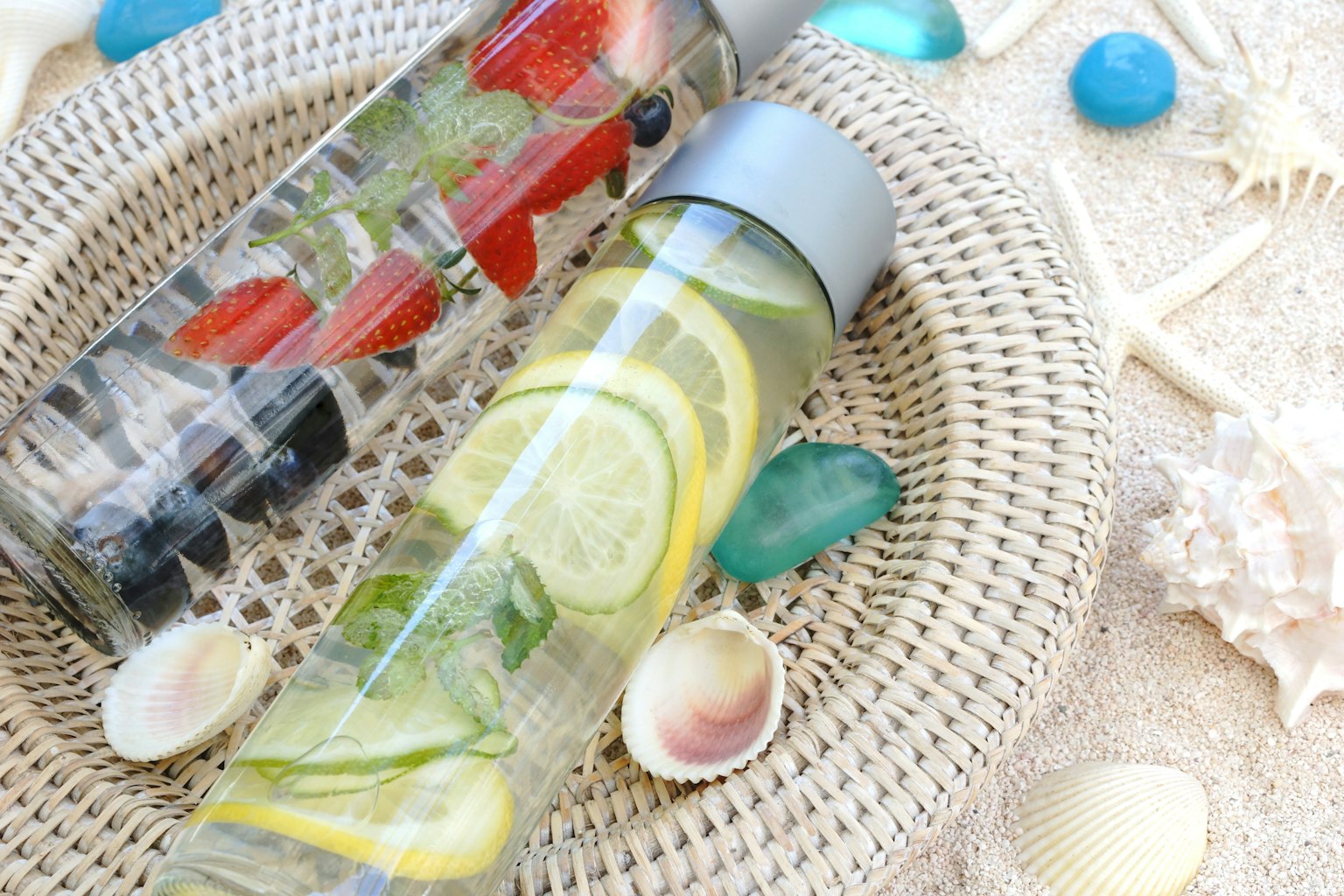 Bouteilles transparentes remplies de fruits et d'herbes sur un plateau tissé