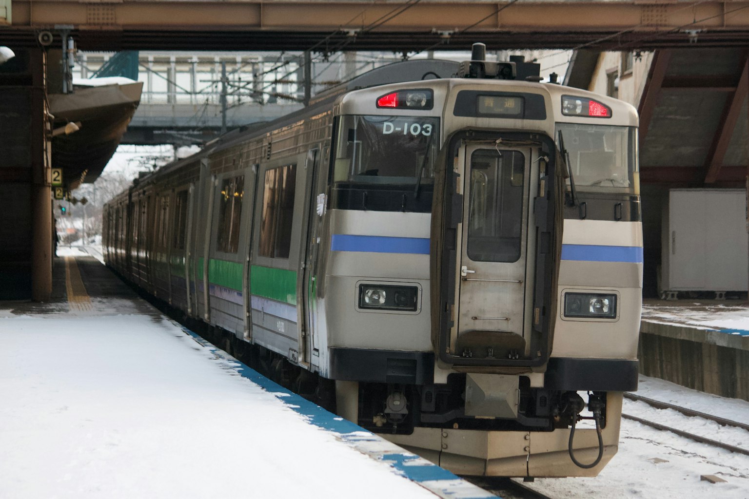Tren detenido en una estación nevada con perfil lateral visible