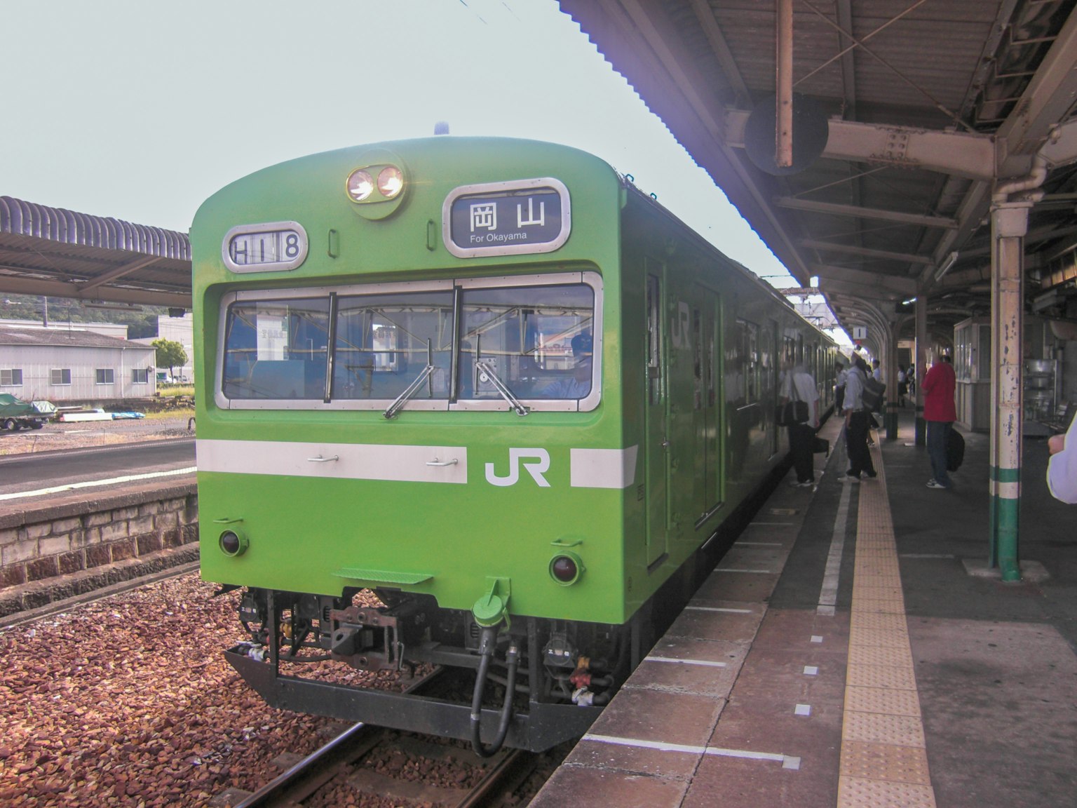 Kereta JR hijau berhenti di stasiun dengan penumpang naik dan turun