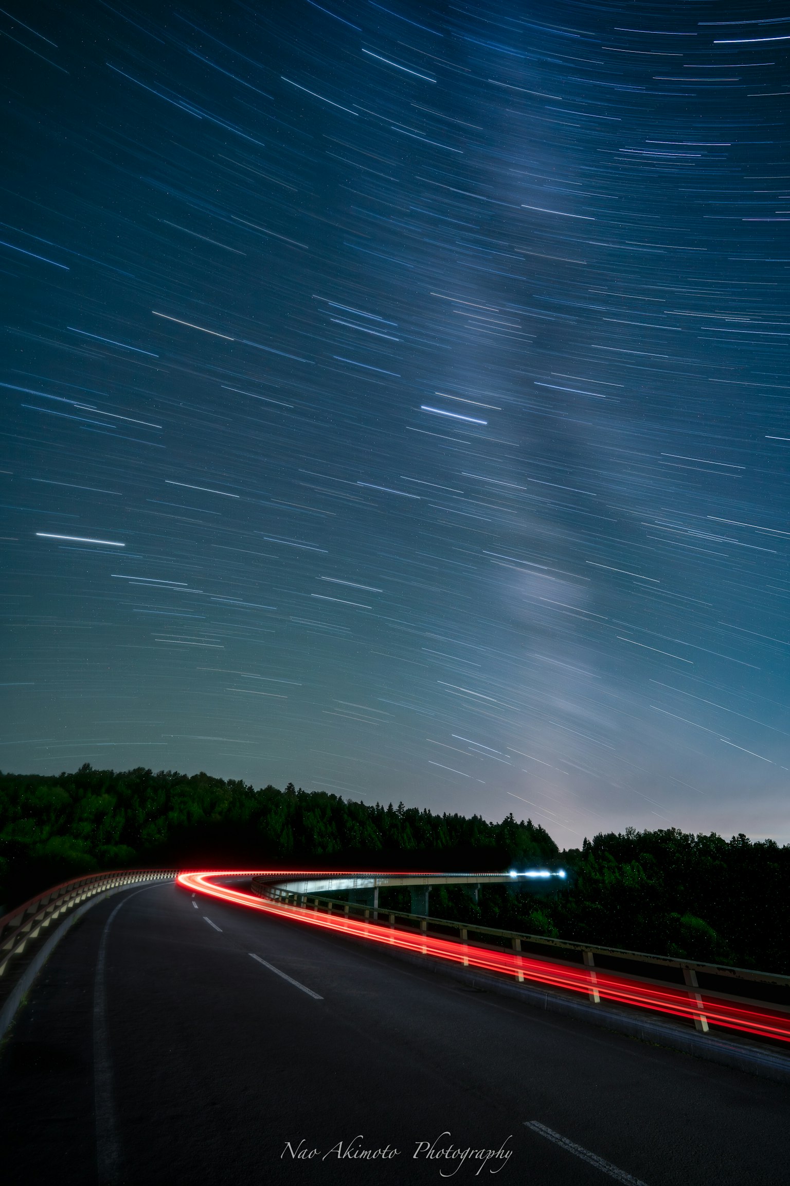 Route nocturne avec des traînées d'étoiles et des lumières de voiture