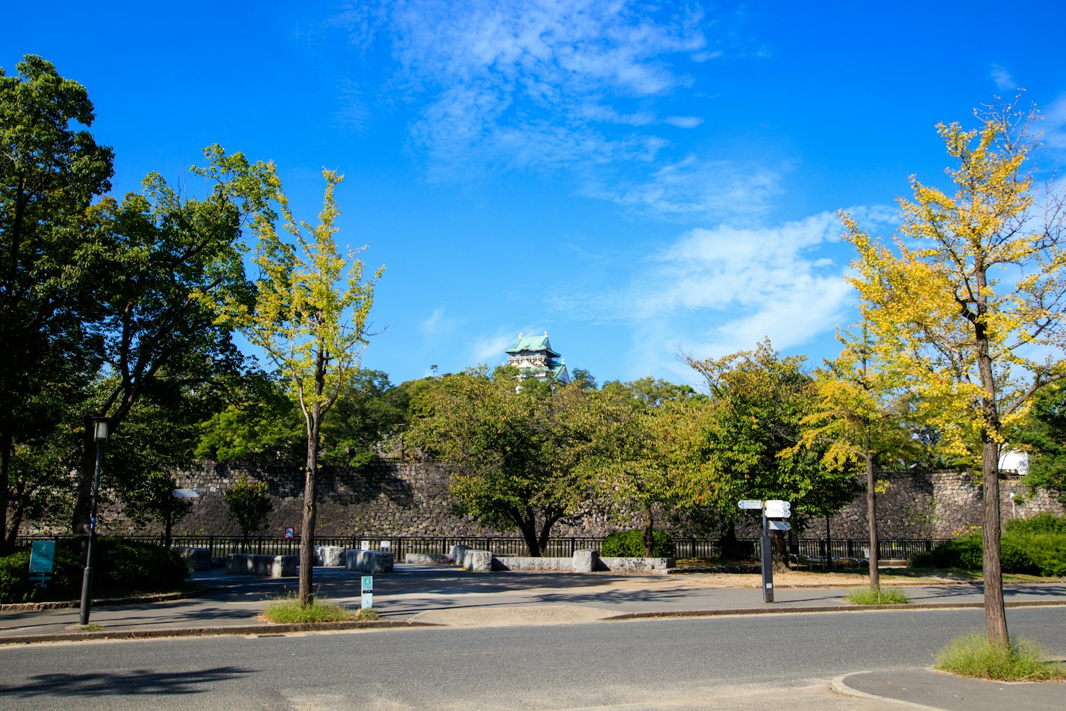 Park scene under blue sky with green and yellow trees