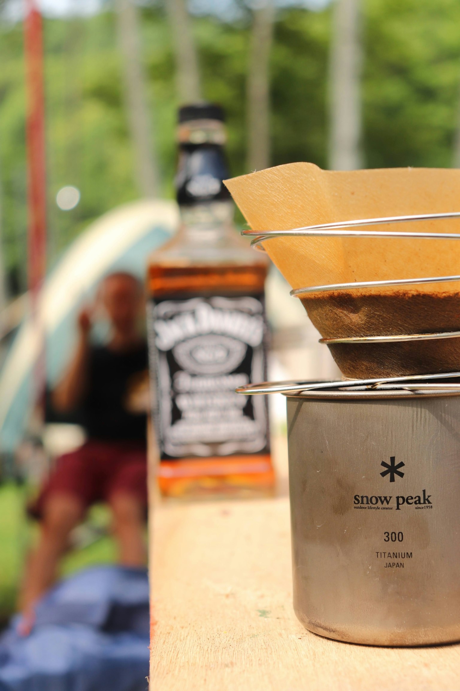 Coffee brewing setup with a Jack Daniel's bottle in a camping scene