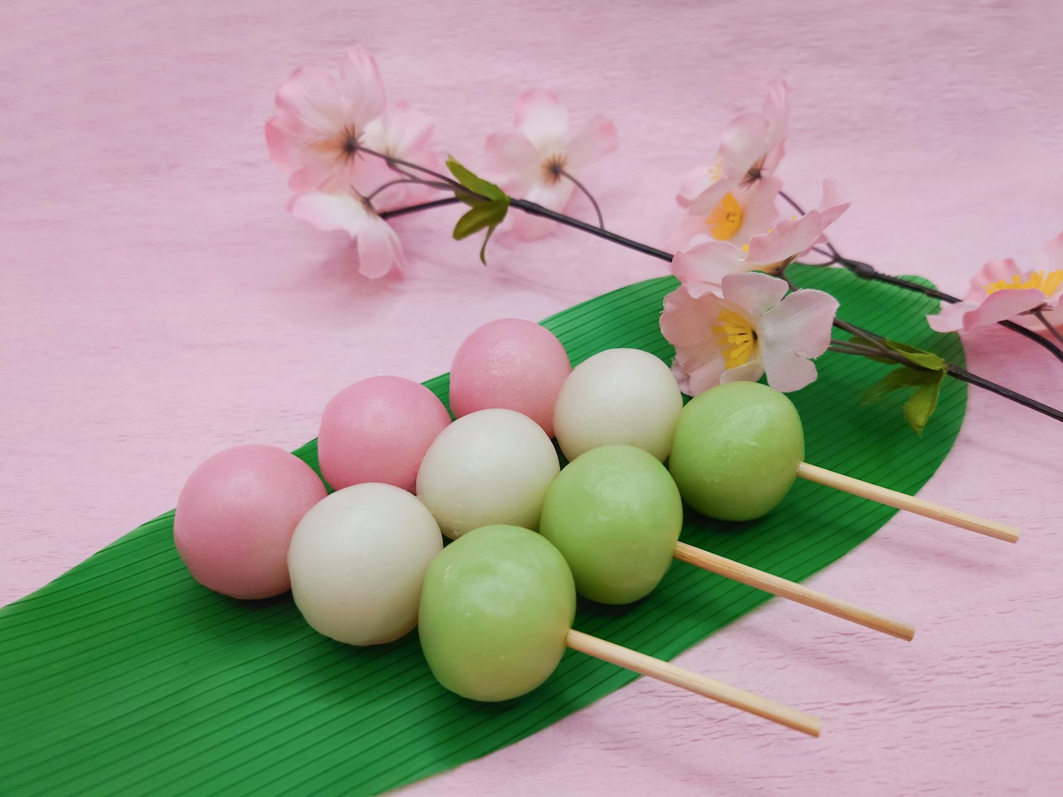 Xiên dango đầy màu sắc với hoa anh đào ở phía sau