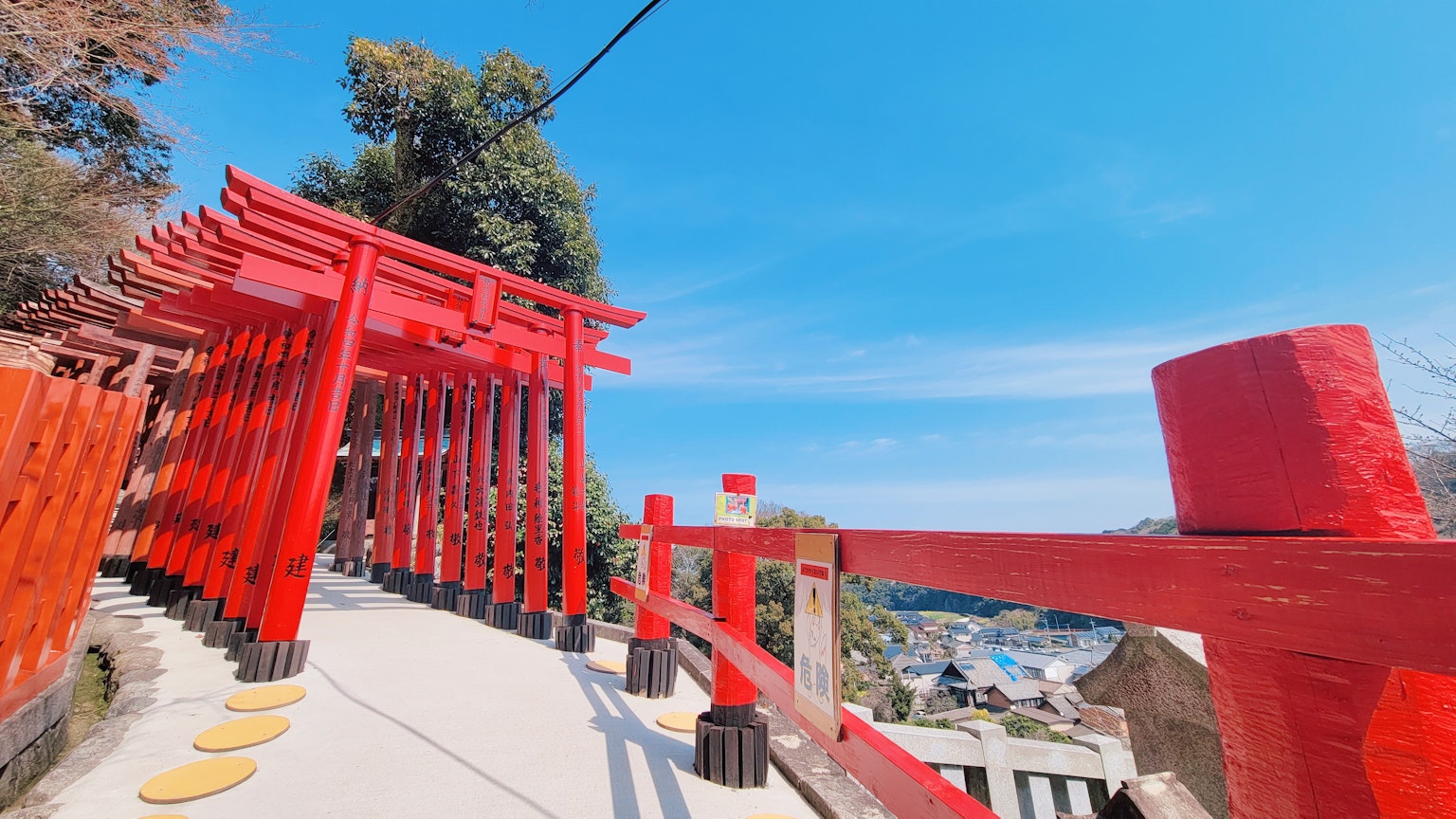 Camino bordeado de puertas torii rojas bajo un cielo azul