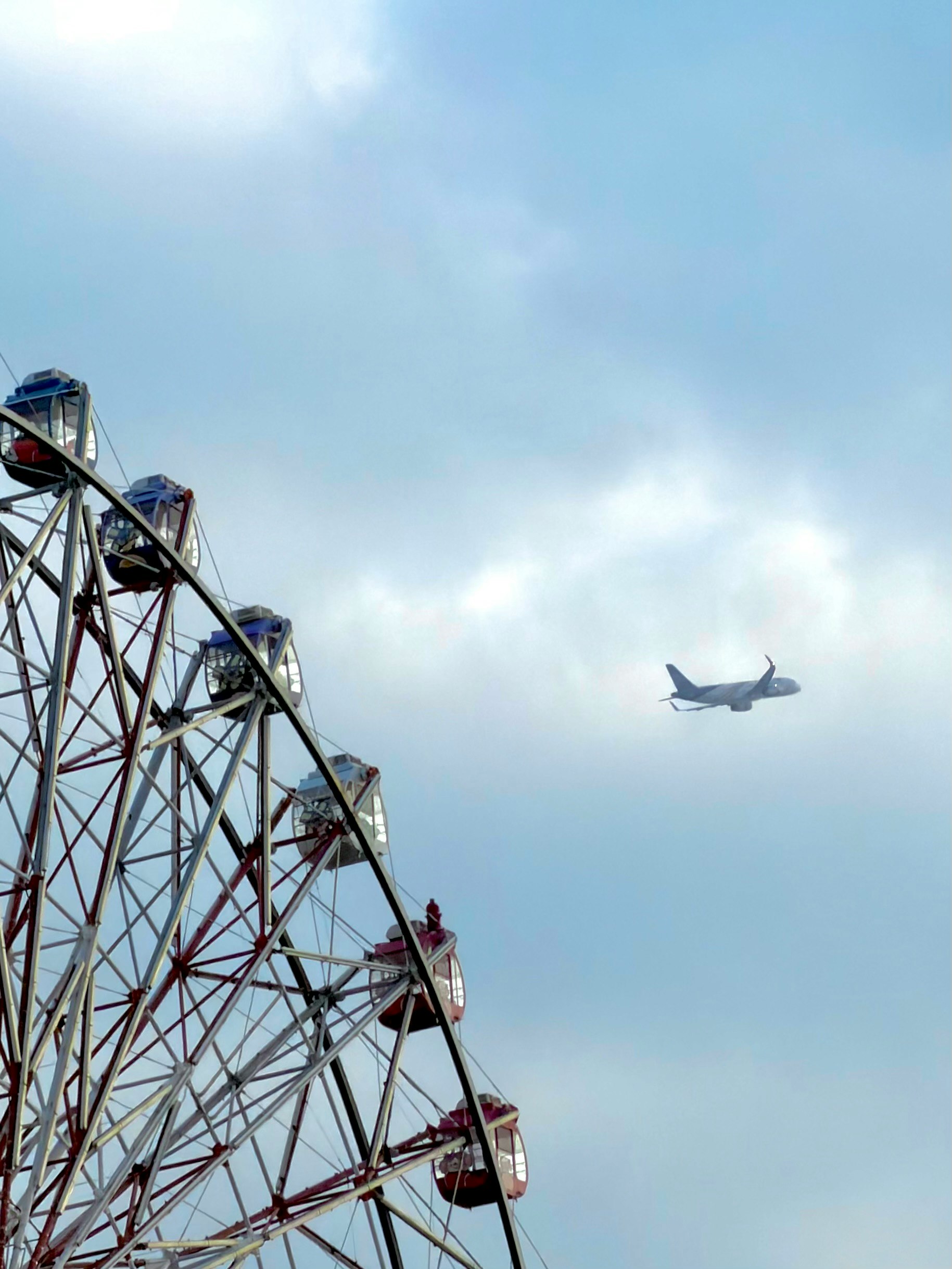 観覧車と飛行機が空に浮かぶ風景