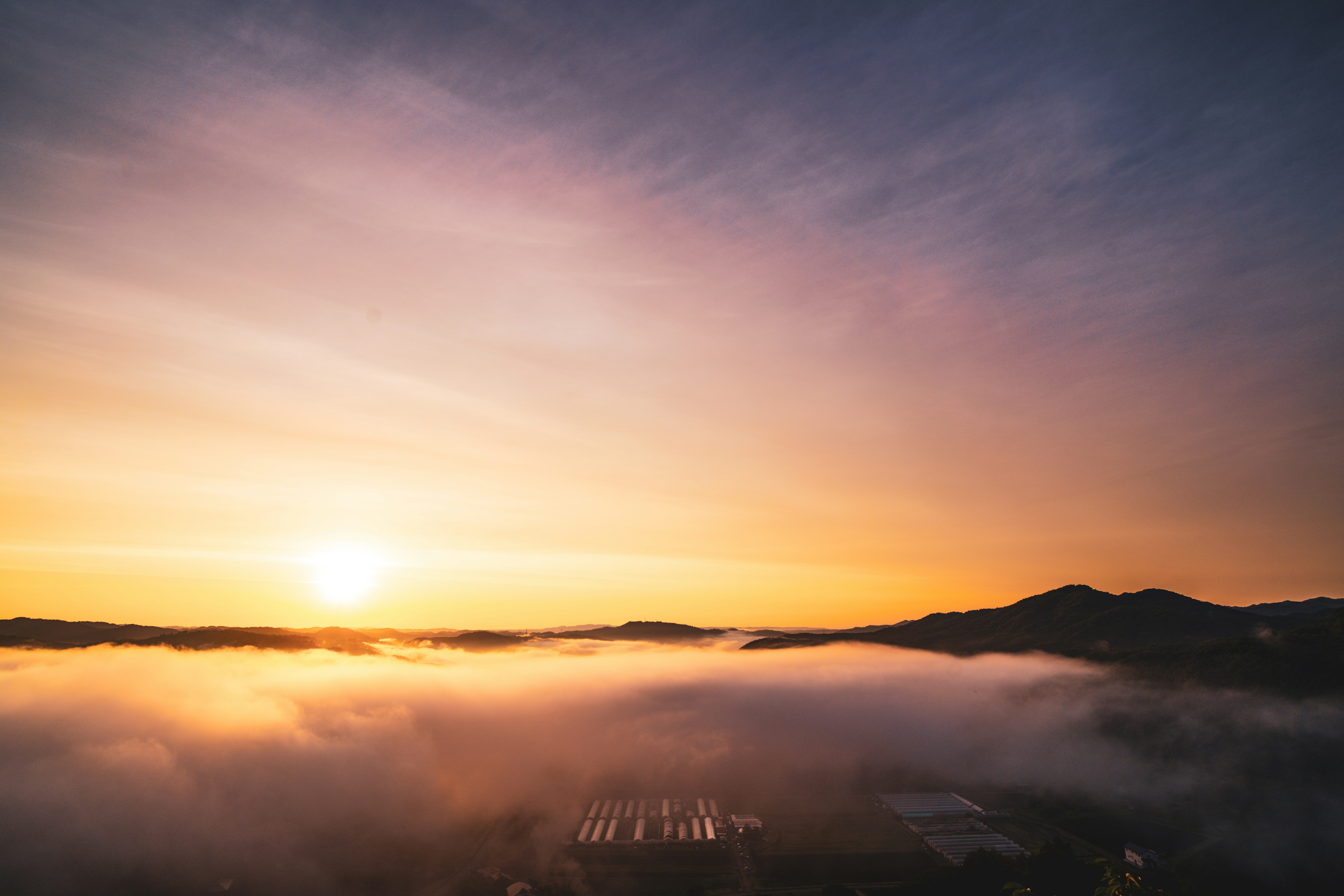 Sunset over a sea of clouds with mountain silhouettes