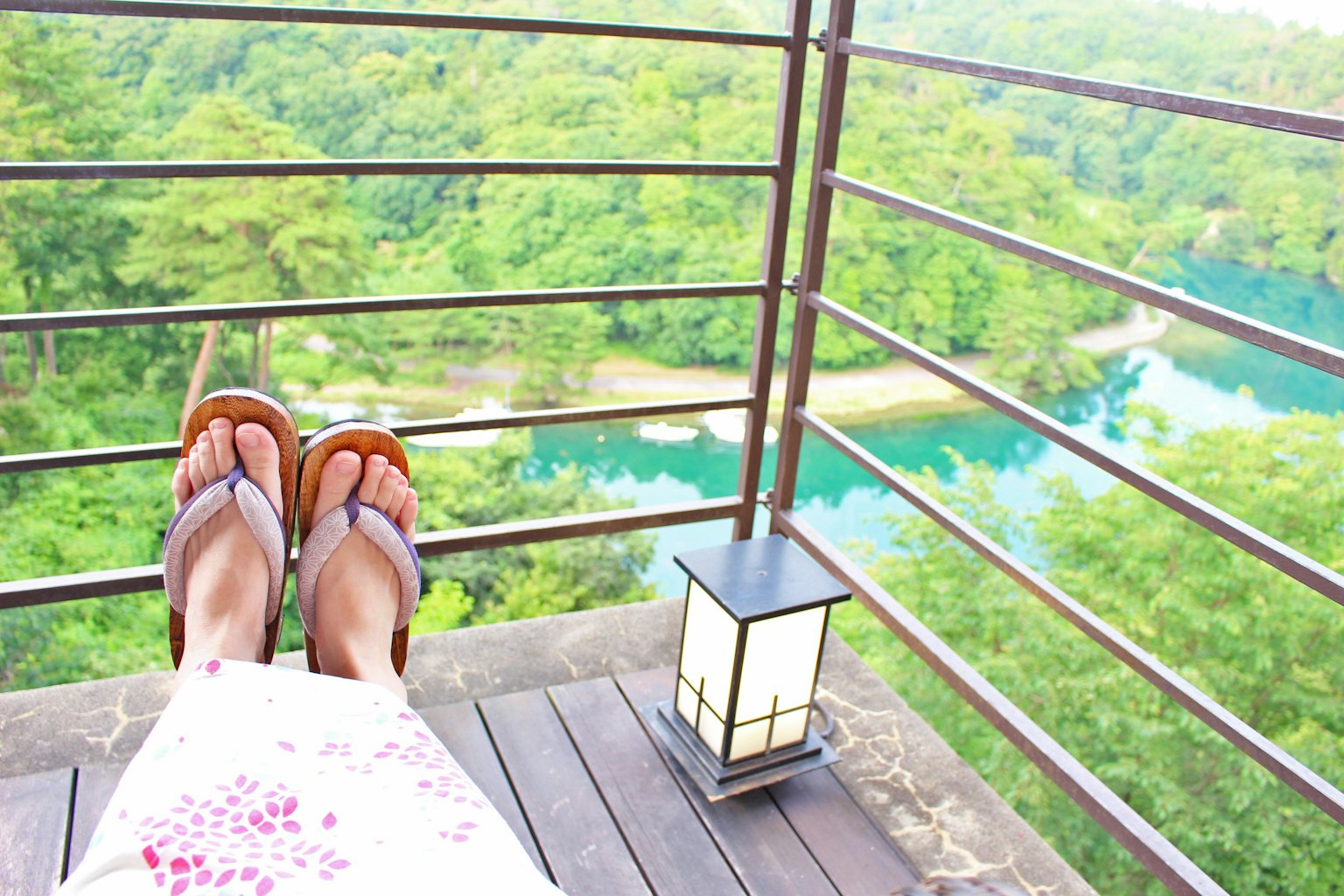 Feet resting on a balcony with a green landscape view