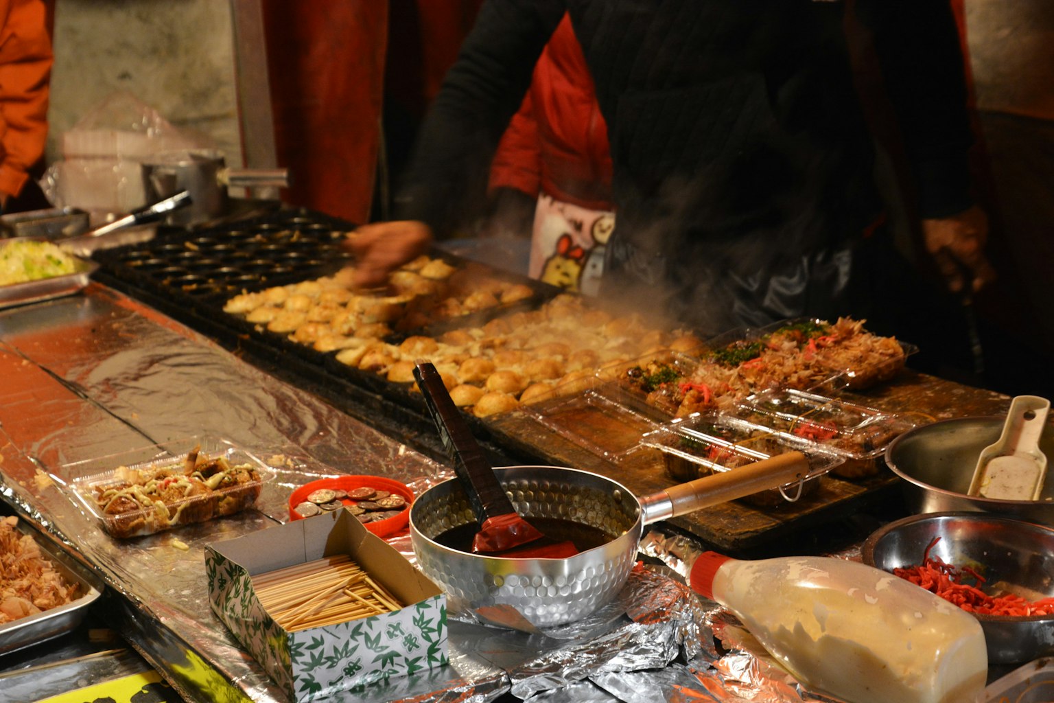 Vendedor ambulante cocinando con varios ingredientes y platos