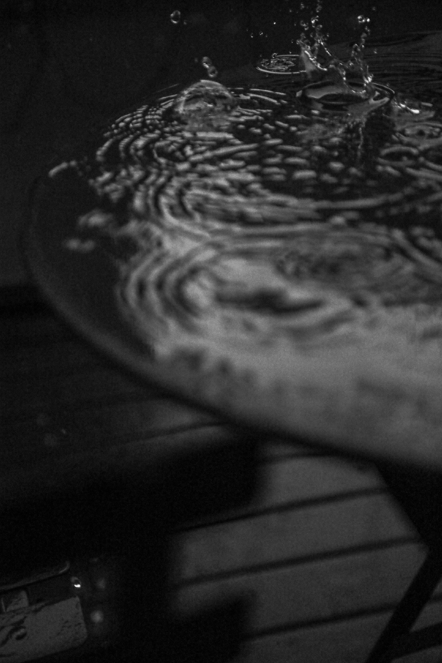 Imagen en blanco y negro de gotas de agua creando ondas en una mesa