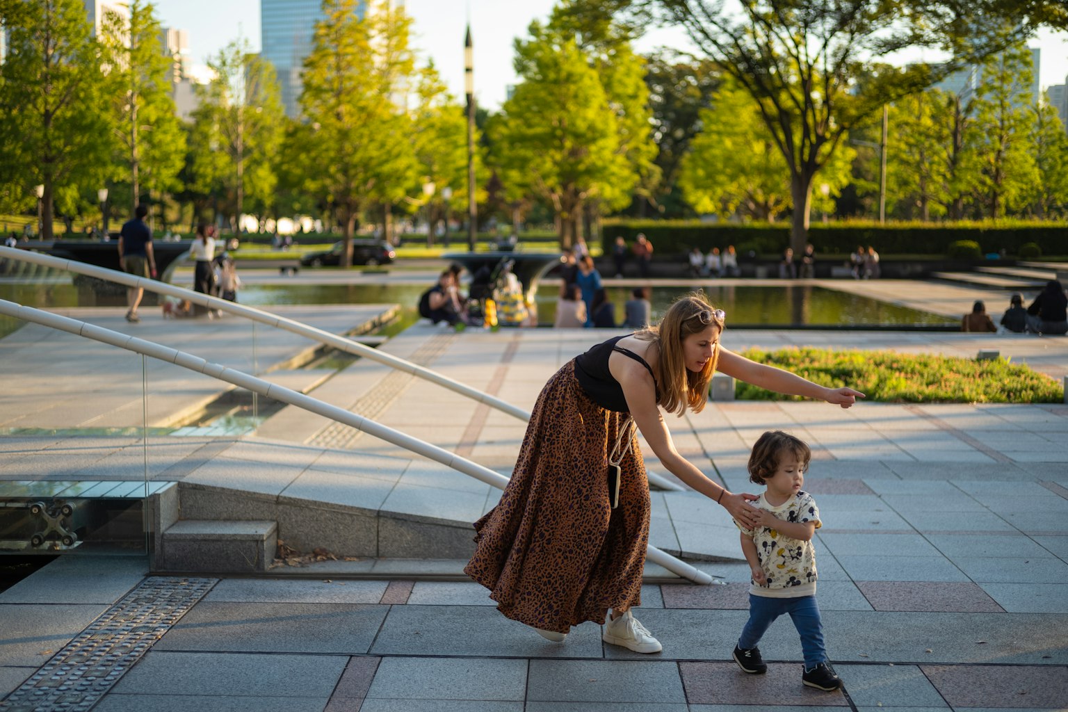 Mother playing with child in a park surrounded by green trees and open space