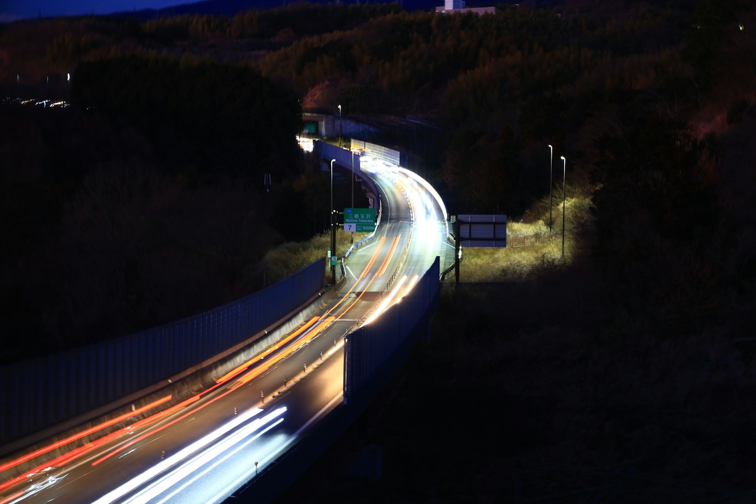 Vista nocturna de una autopista con estelas de luz de vehículos en movimiento