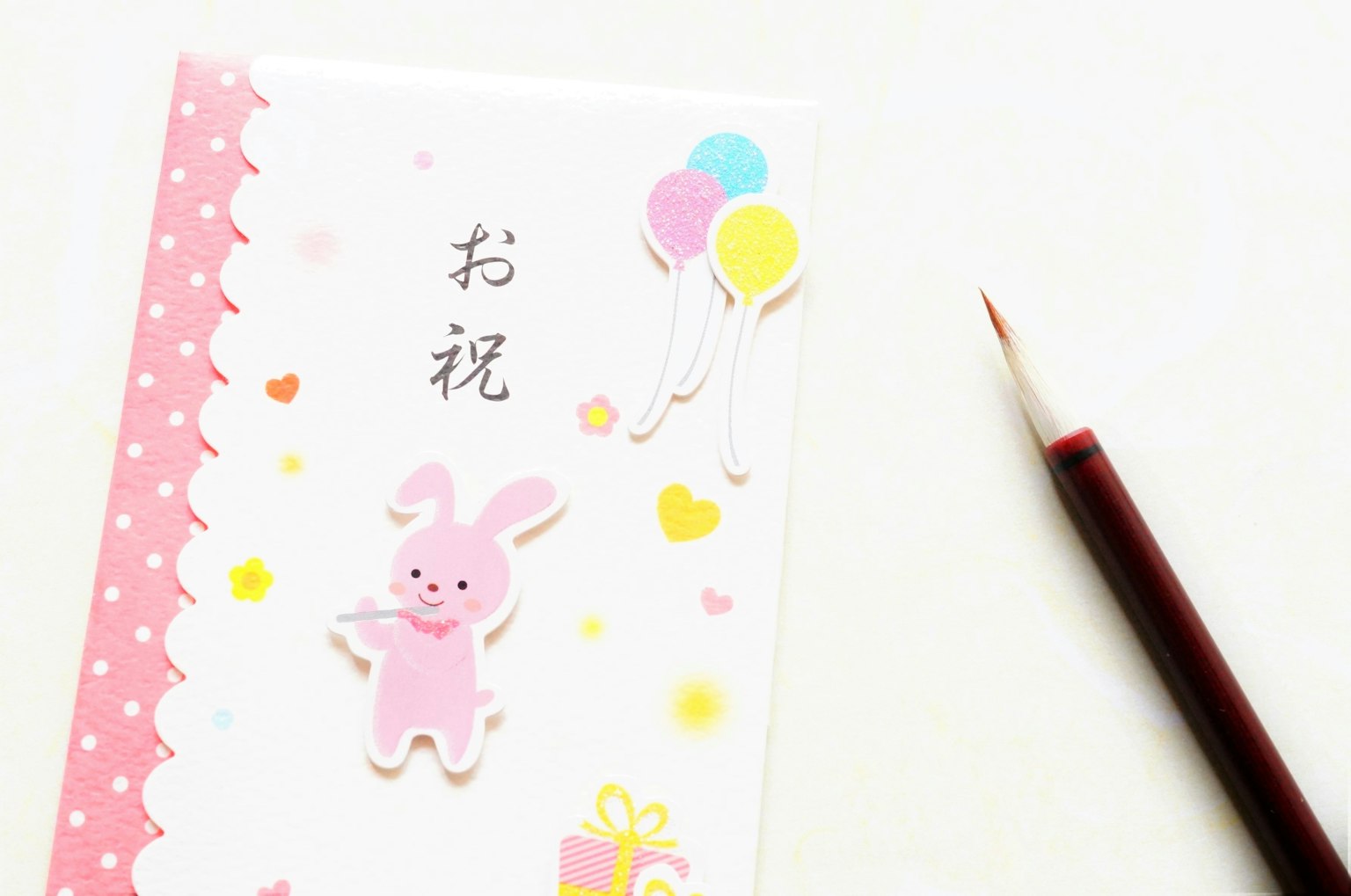 การ์ดเฉลิมฉลองที่มีภาพการ์ตูนกระต่ายสีชมพูและลูกโป่งหลากสี