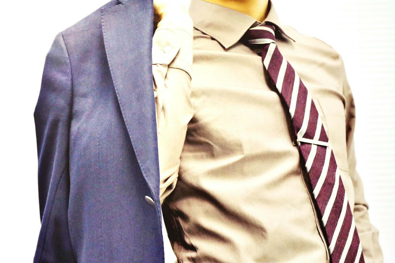 An image showcasing a split view of a suit on one side and a business shirt with a tie on the other