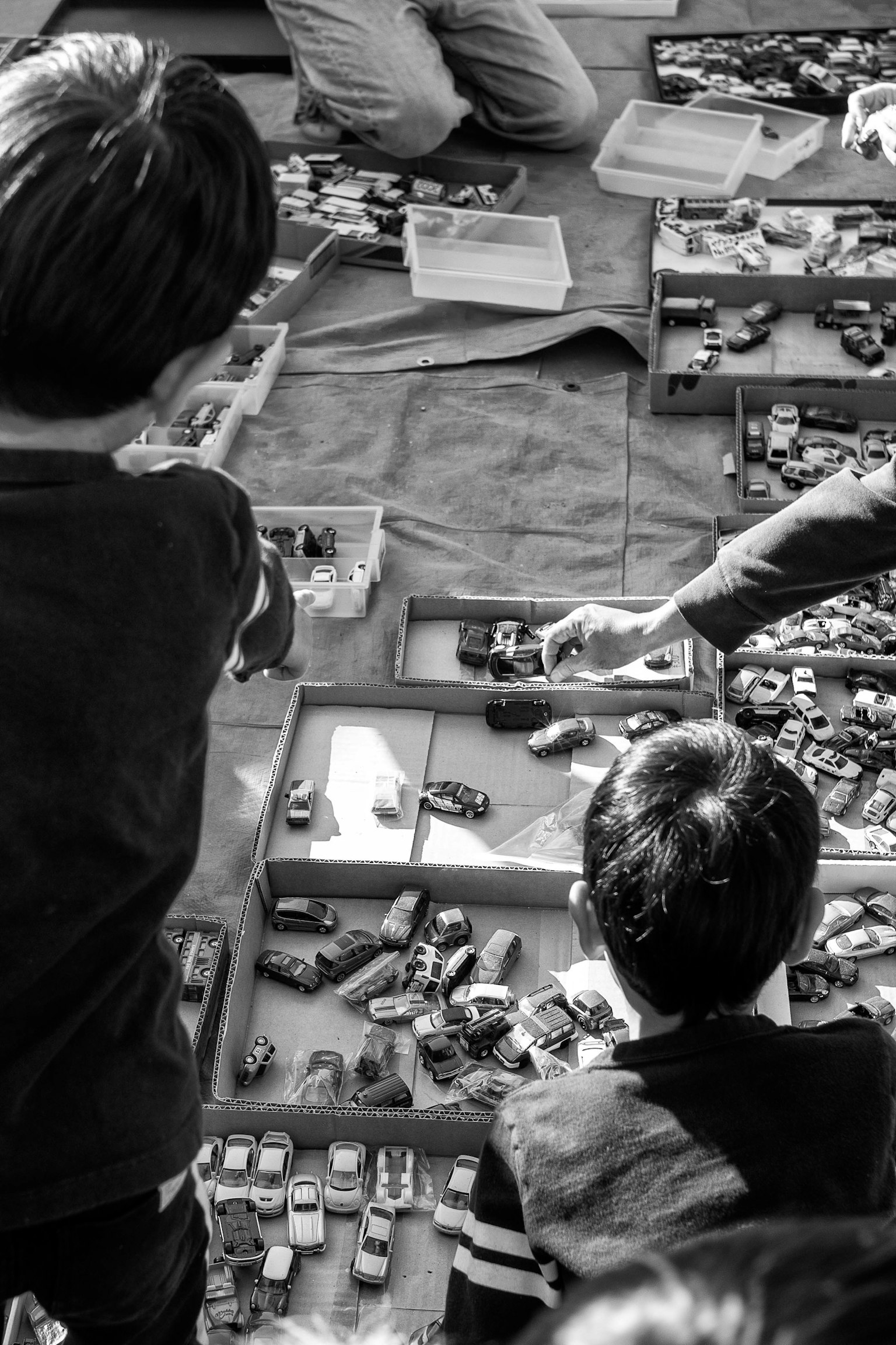 Black and white photo of children selecting toy cars