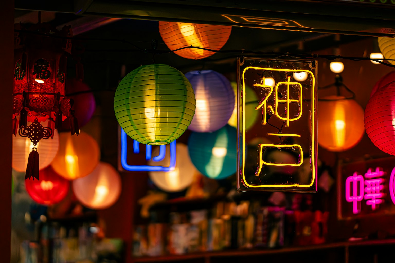 五彩繽紛的燈籠裝飾著街頭小販場景，突出顯示神戶的霓虹招牌