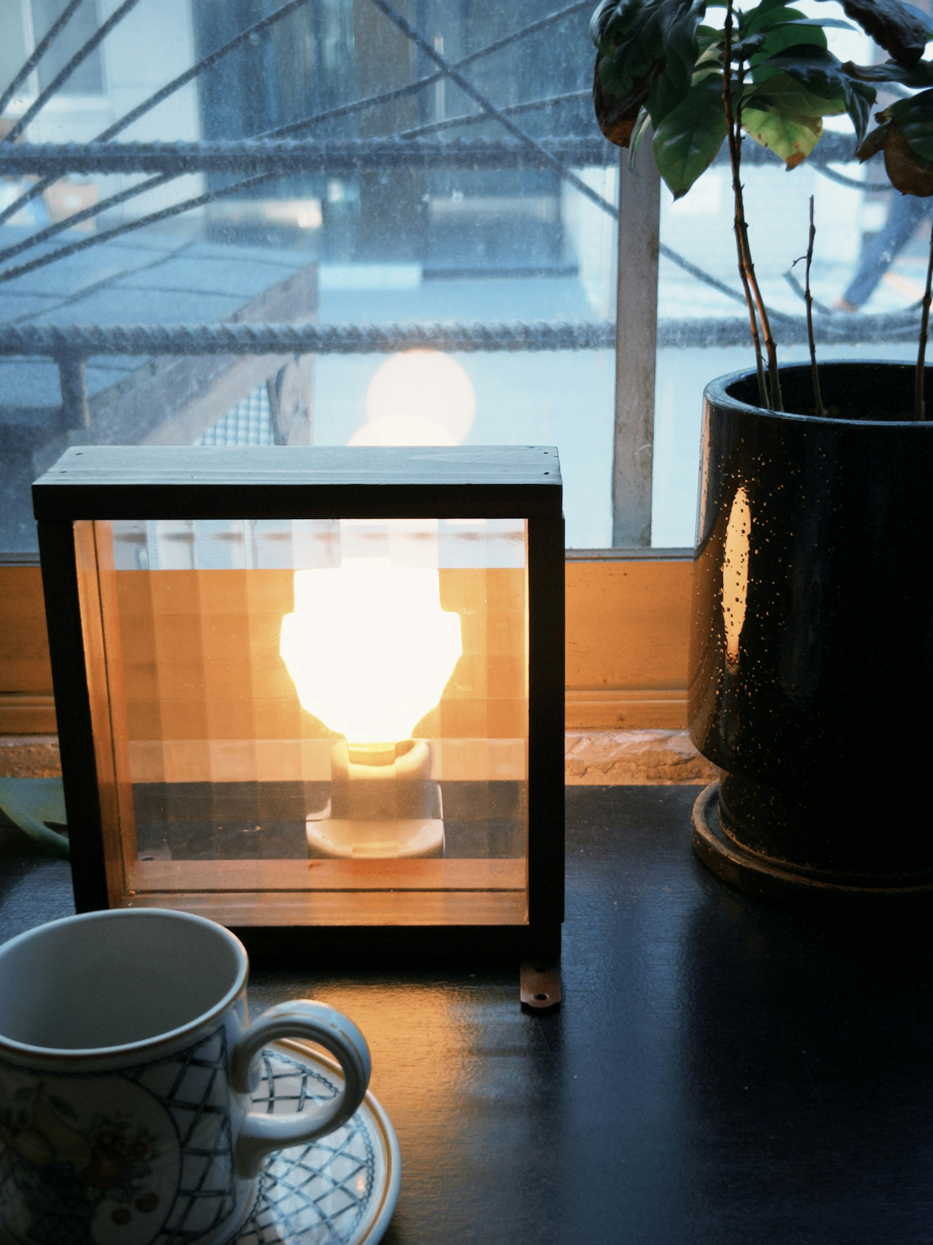 ガラス越しに見えるコーヒーの湯気とカップのある室内カフェ空間