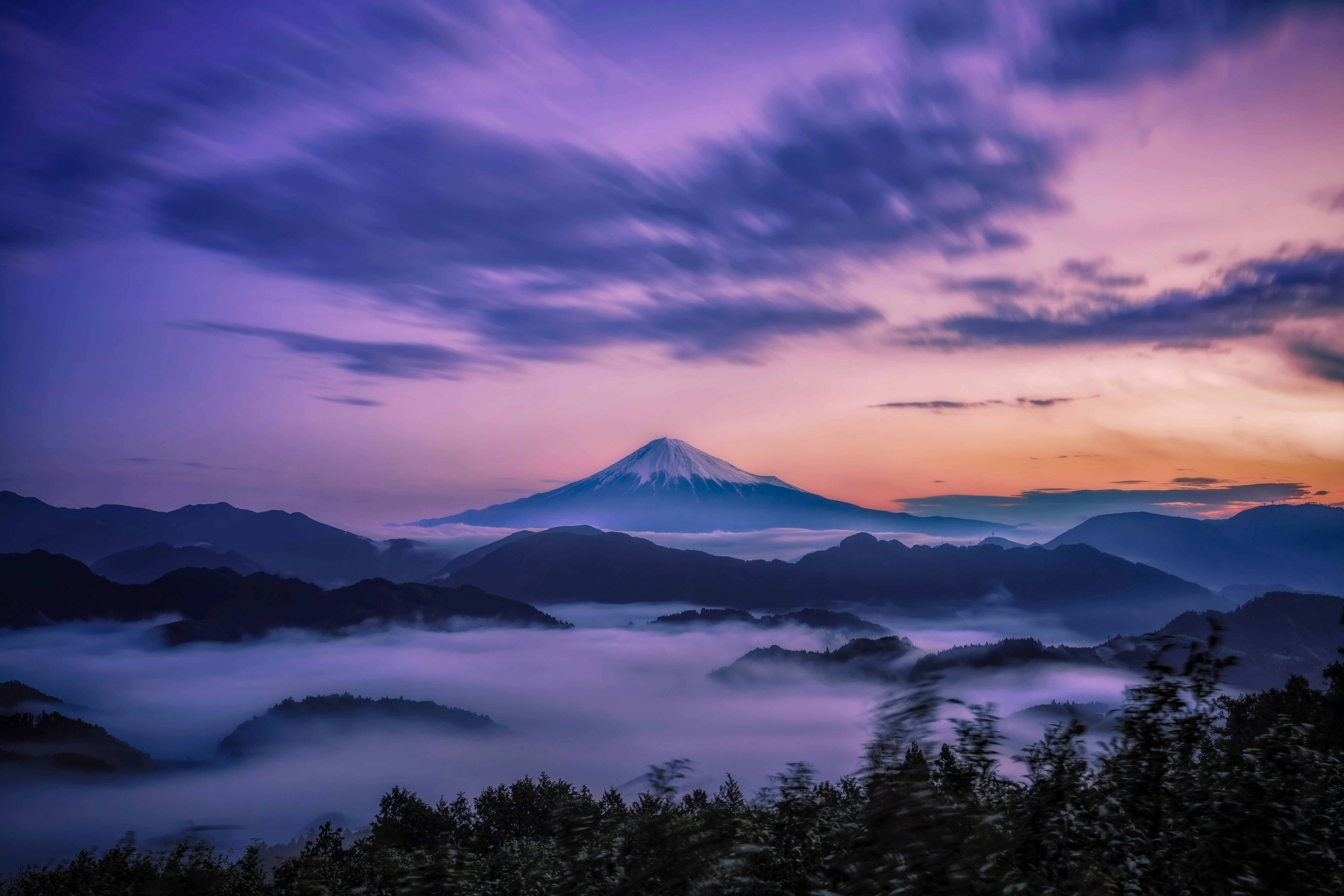霧に包まれた山並みと夕焼けの富士山