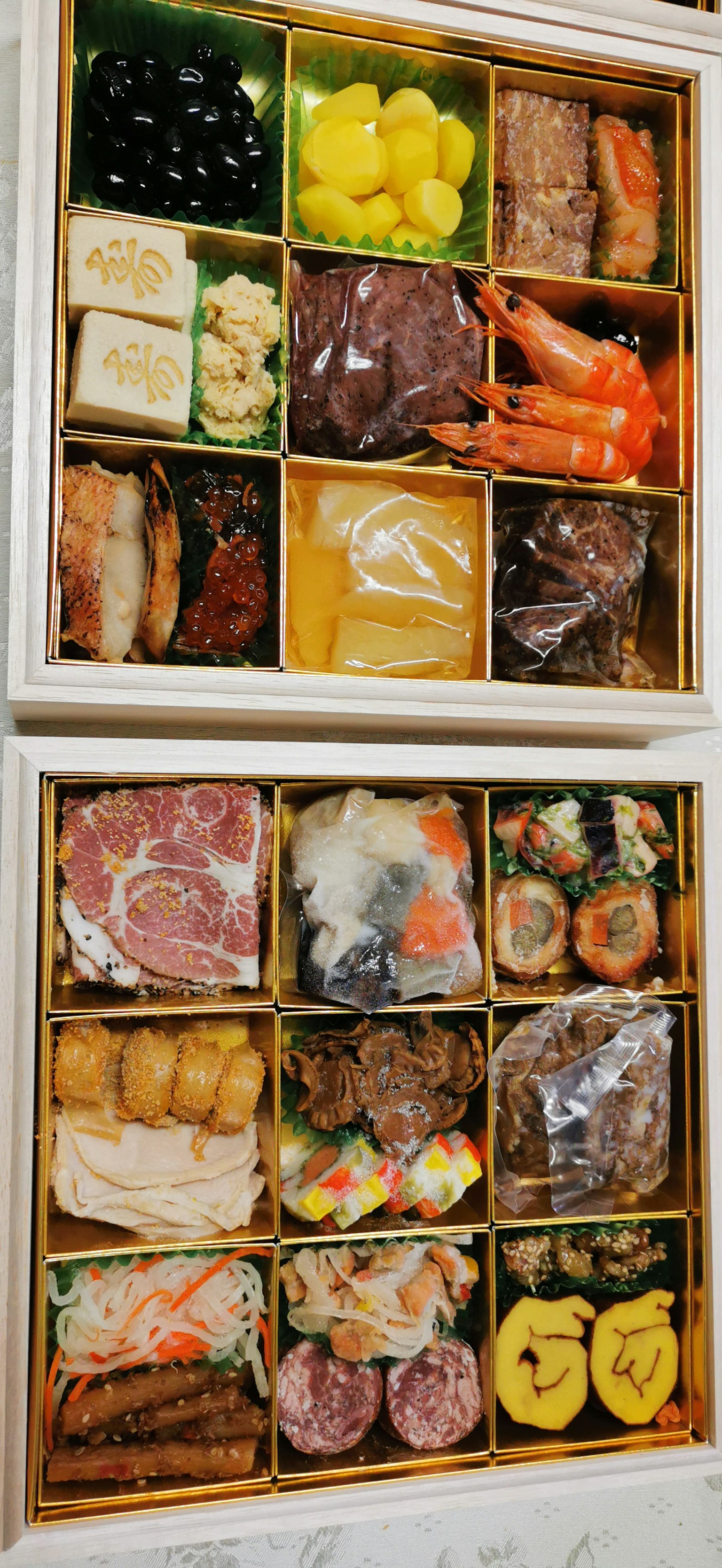 Boîte à bento à deux niveaux remplie de sushi et de plats traditionnels d'osechi joliment présentés