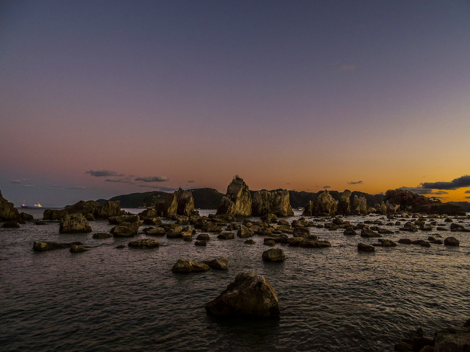 Rocas dispersas en el mar al atardecer con un cielo colorido