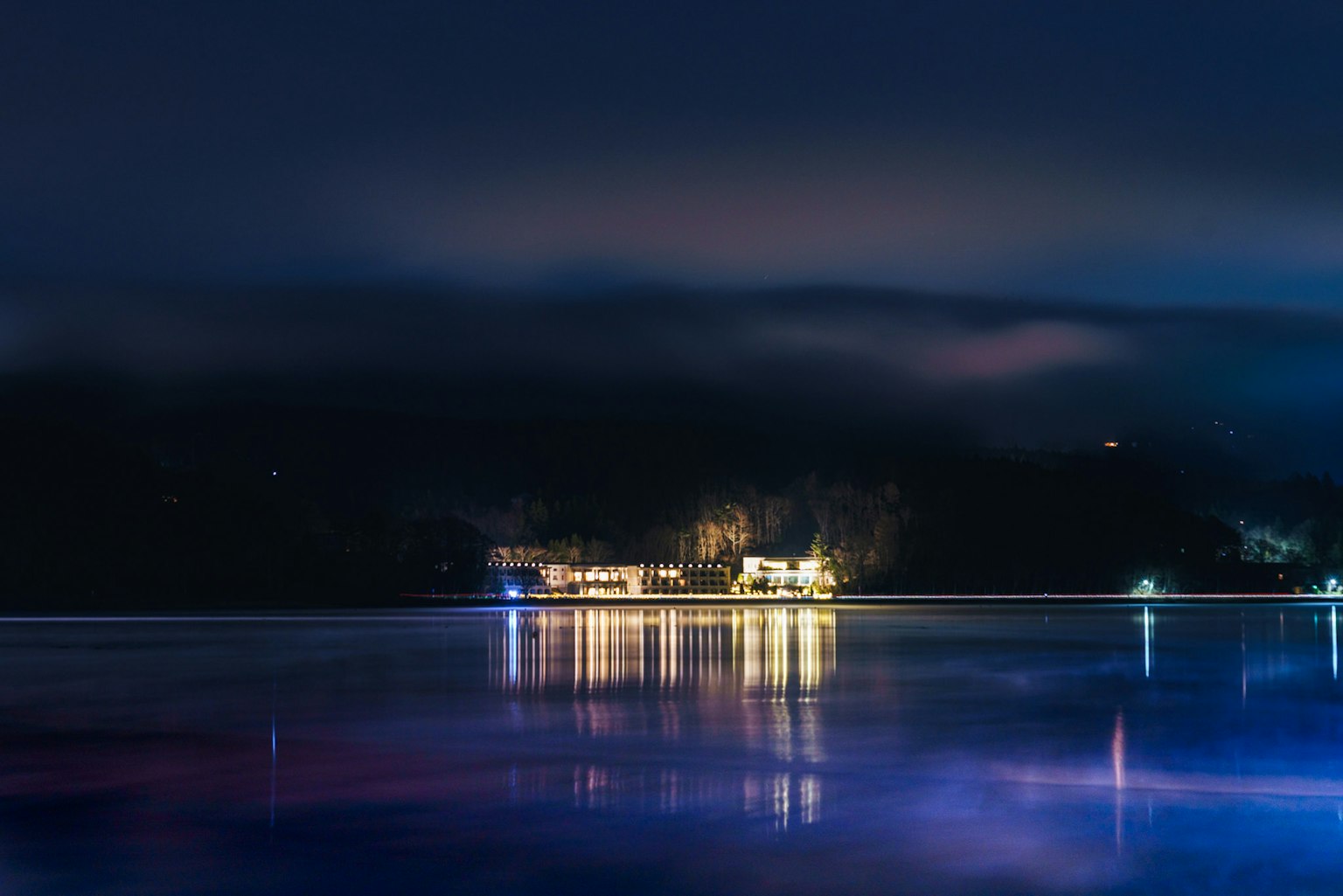 Paesaggio notturno con luci che si riflettono sul lago