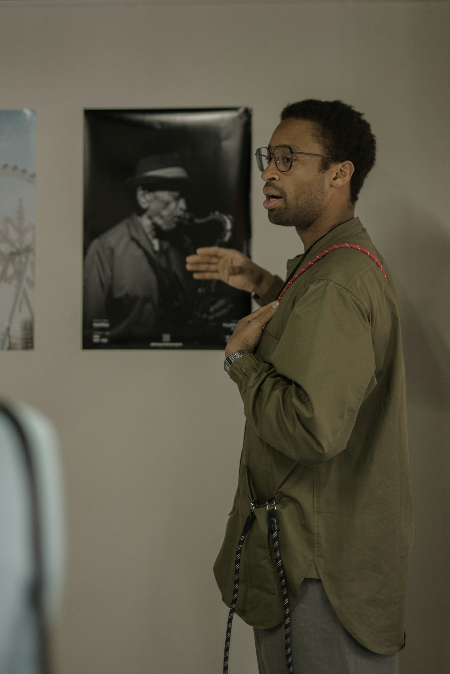 Ein Mann spricht vor einem Poster mit einem Schwarzweißfoto an der Wand