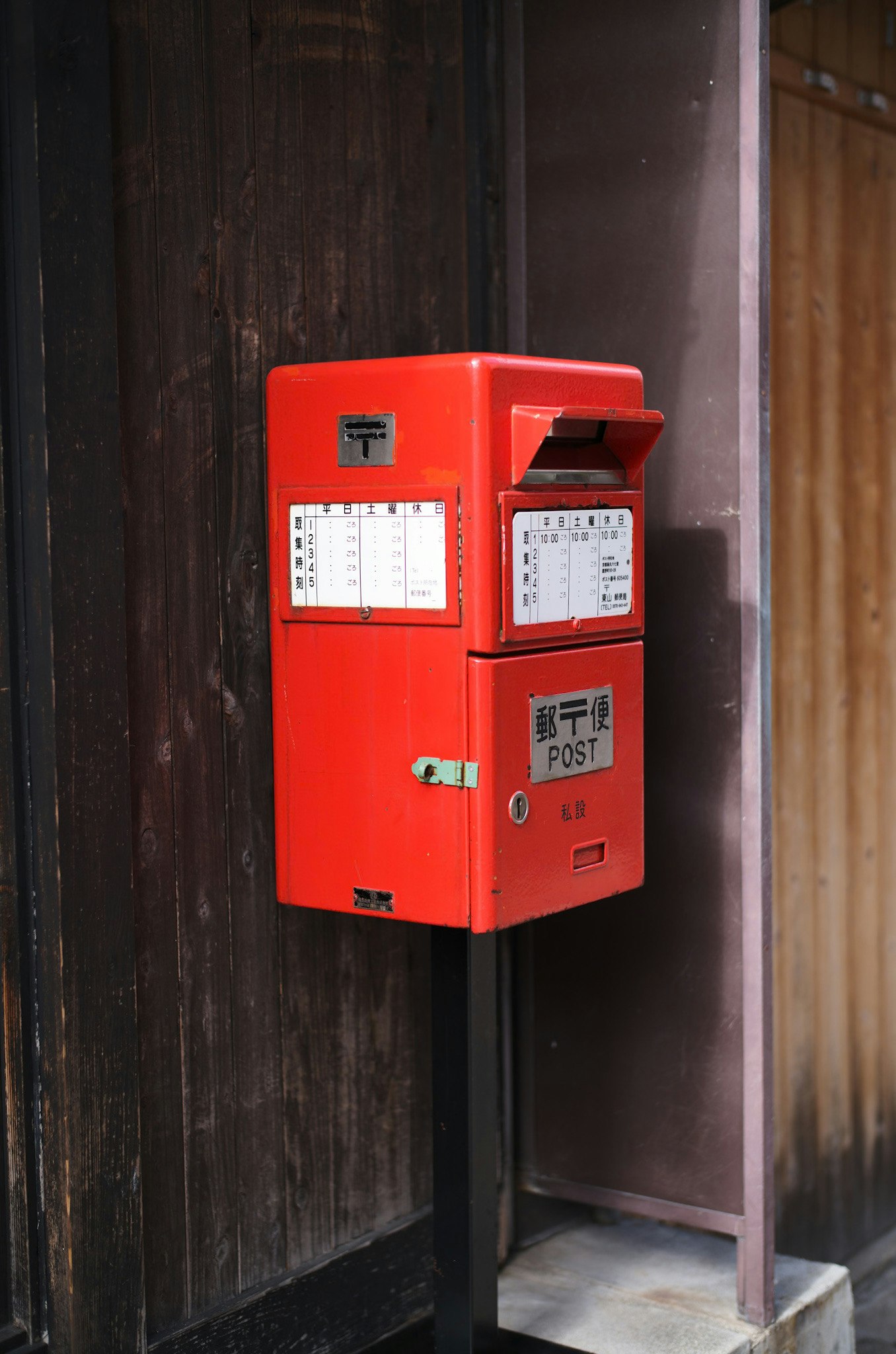 赤い郵便ポストのある木製の壁の前の郵便投函口