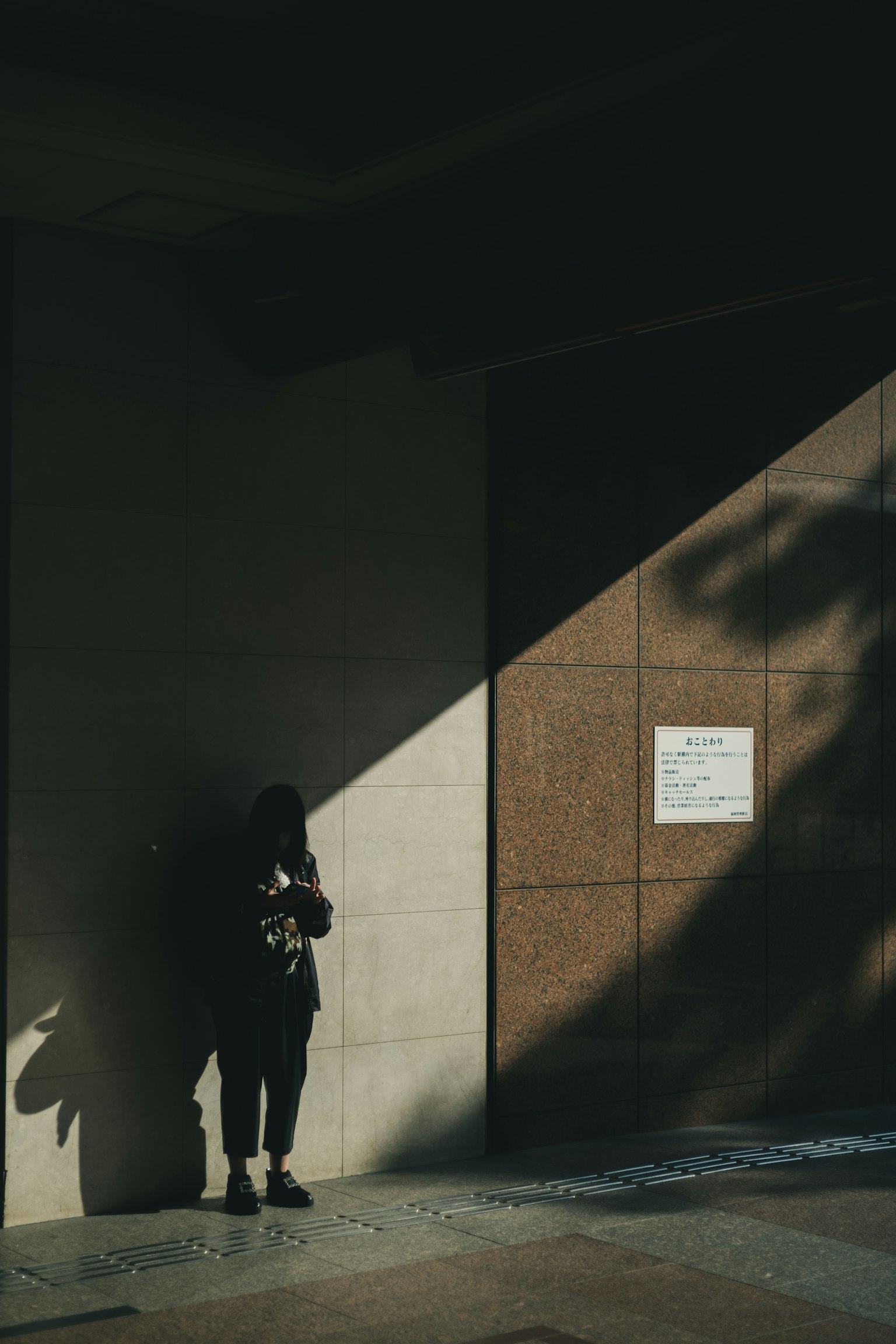 Une silhouette d'une personne se tenant contre un mur avec des ombres et un contraste de lumière dramatiques