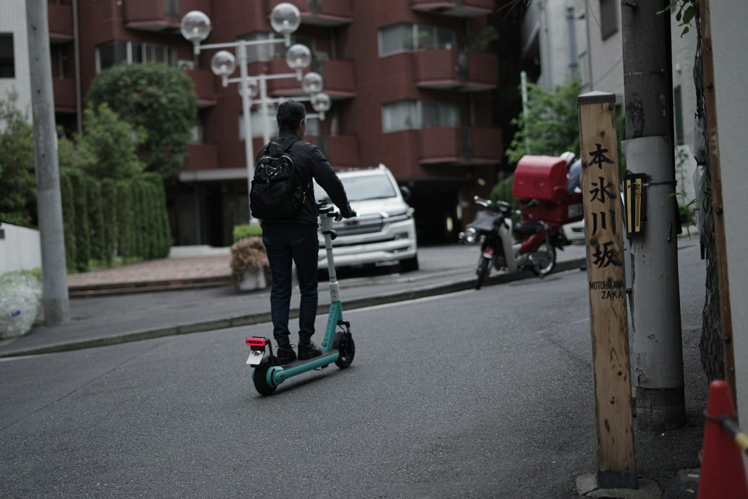 Un homme en vêtements noirs roulant sur un scooter électrique dans un environnement urbain