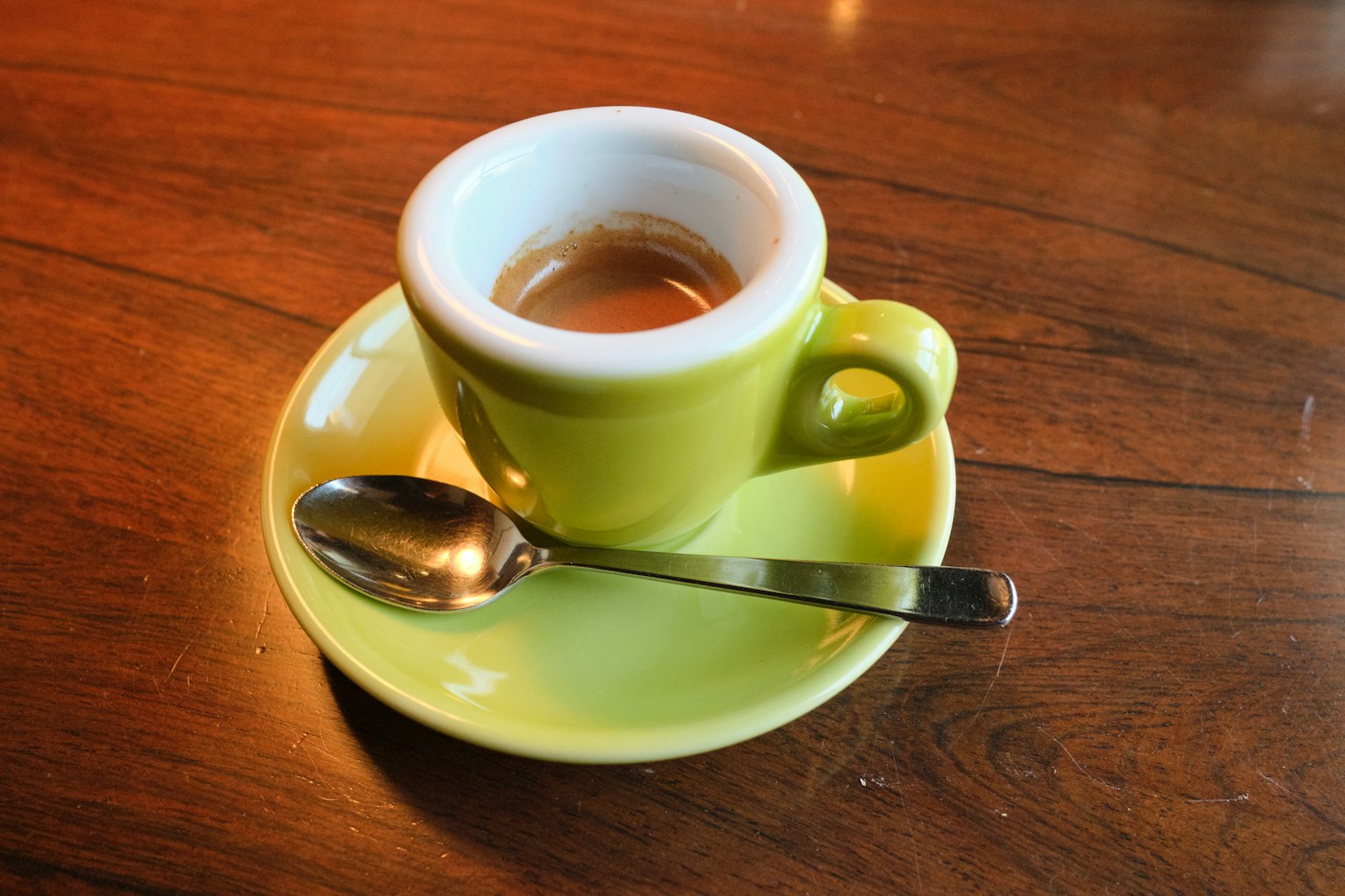 Espresso dalam cangkir hijau dengan sendok perak