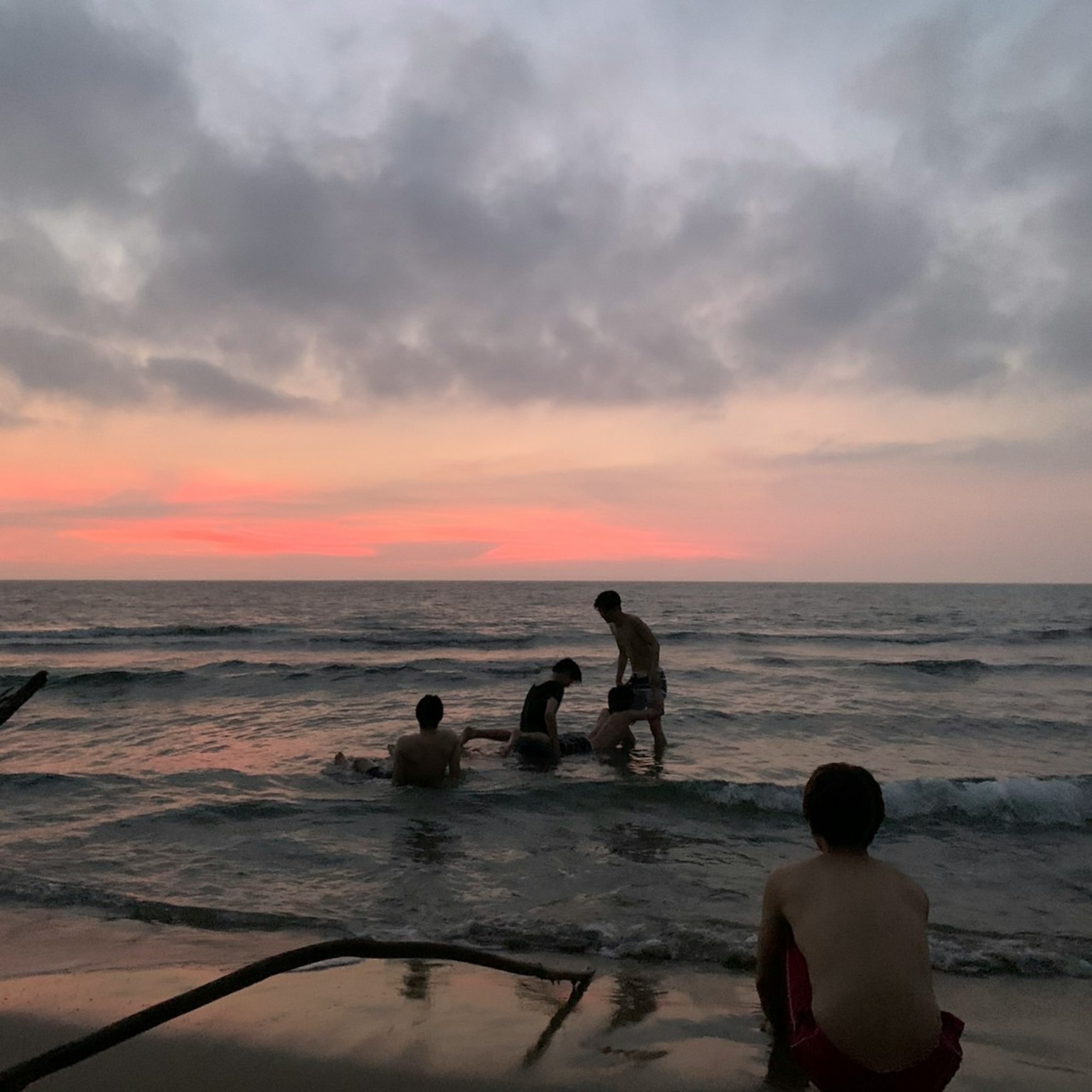 Children playing in the ocean during sunset