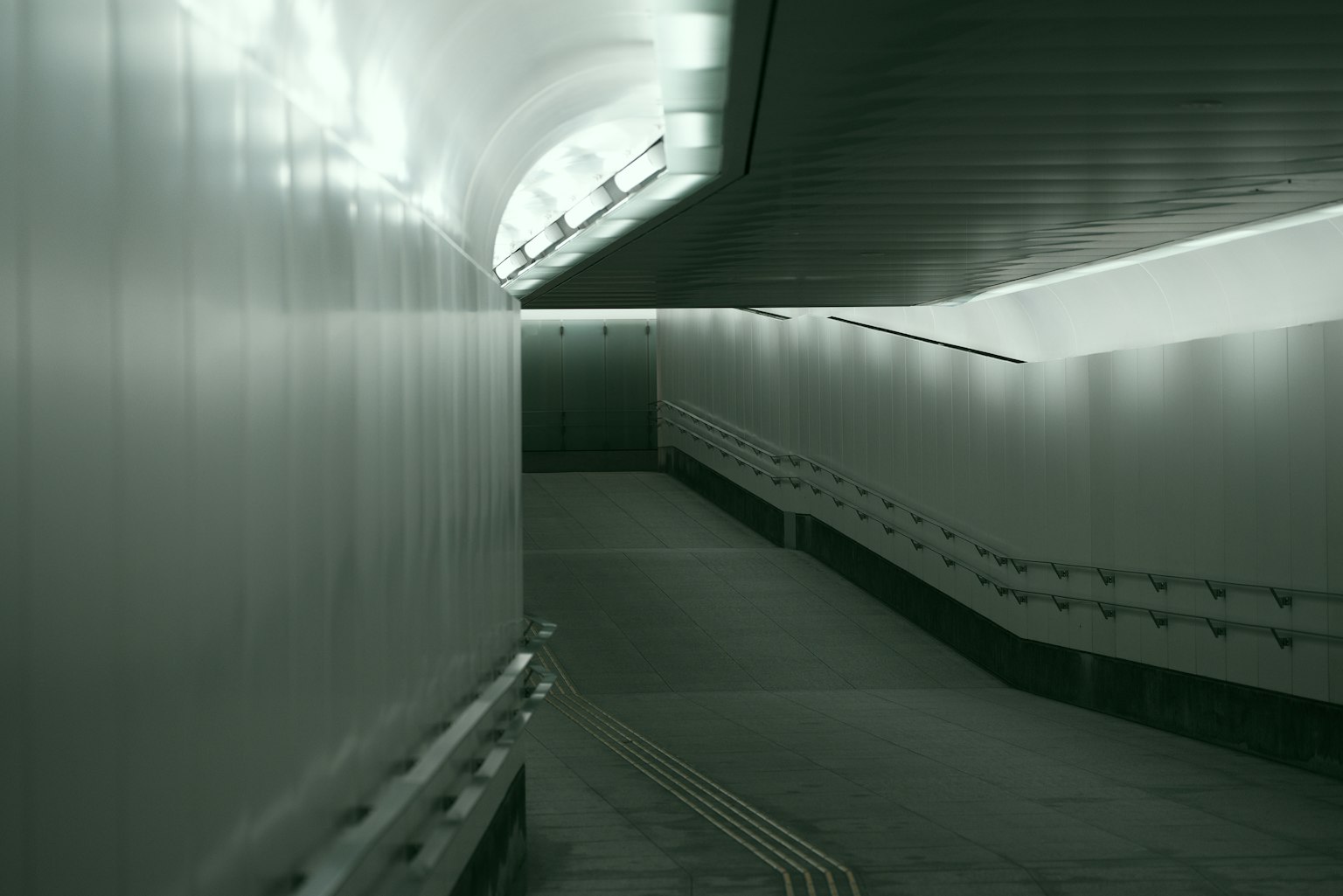 Pasillo moderno curvado con iluminación blanca brillante y paredes lisas