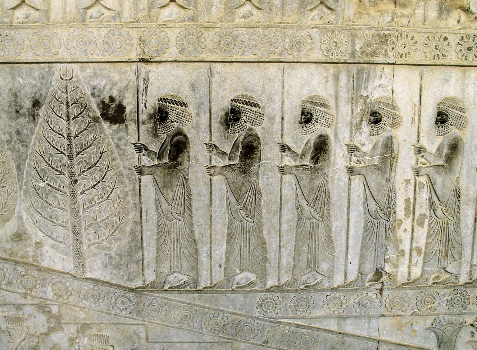 Ancient carving depicting figures holding a large leaf
