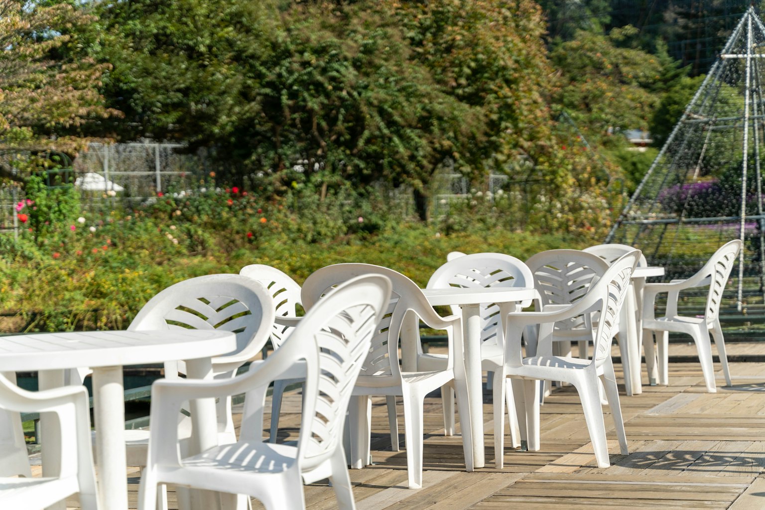 Row of white plastic tables and chairs along a wooden deck