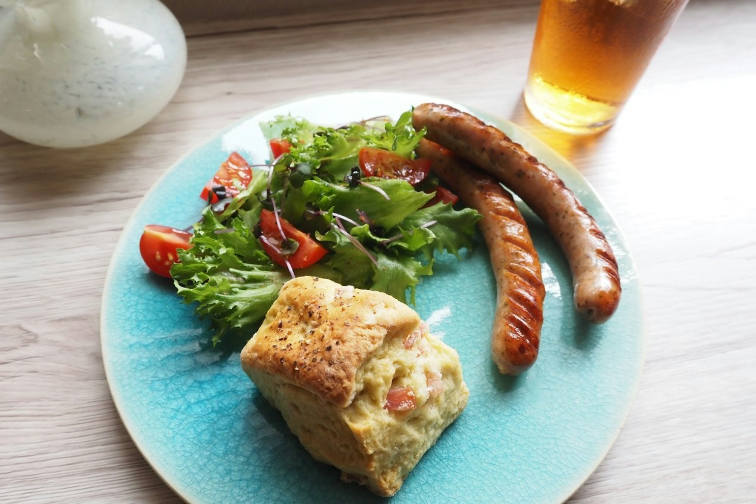 Un plato azul con ensalada, salchichas y un producto horneado